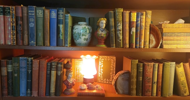 A bookshelf filled with lots of books and a lit candle