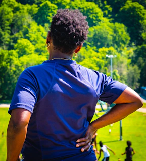 A woman standing in a park with her back to the camera