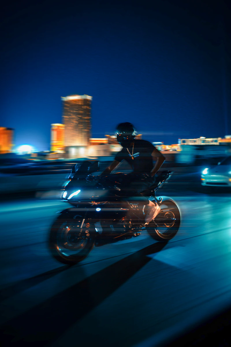 Motorcycle rider speeding through neon-lit city streets at night with motion blur