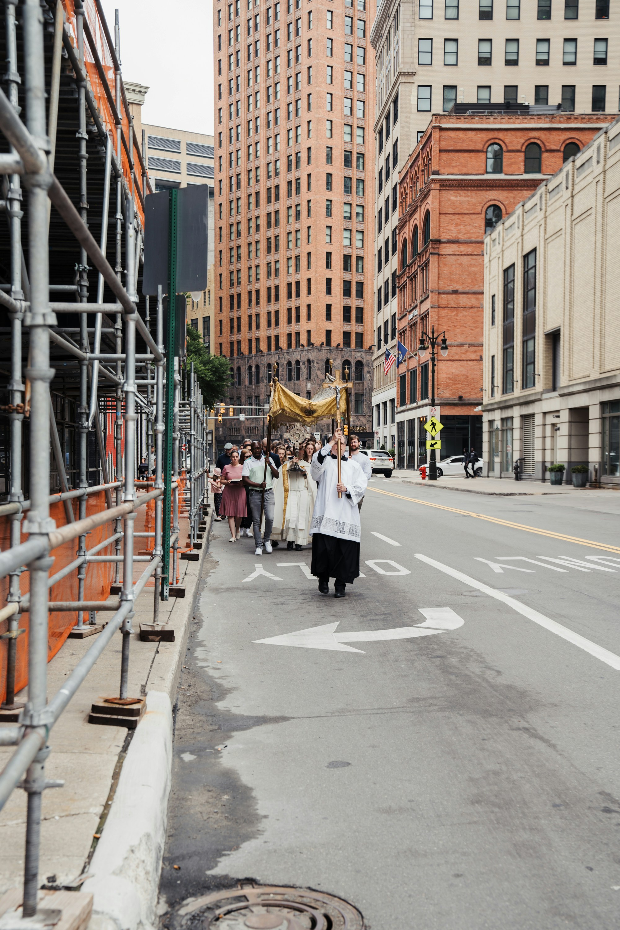 A group of people walking down a street next to tall buildings