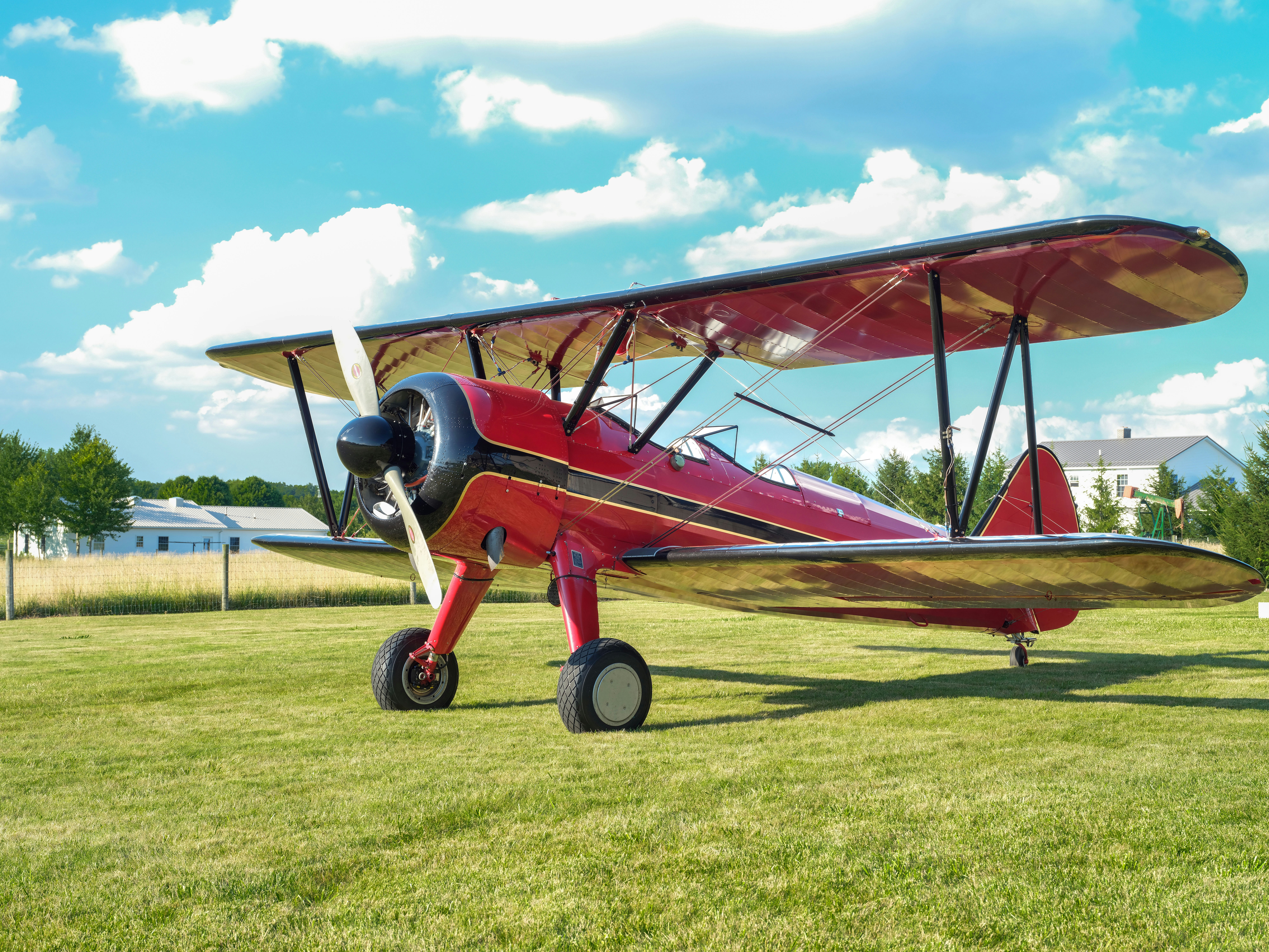 A small red airplane sitting on top of a lush green field