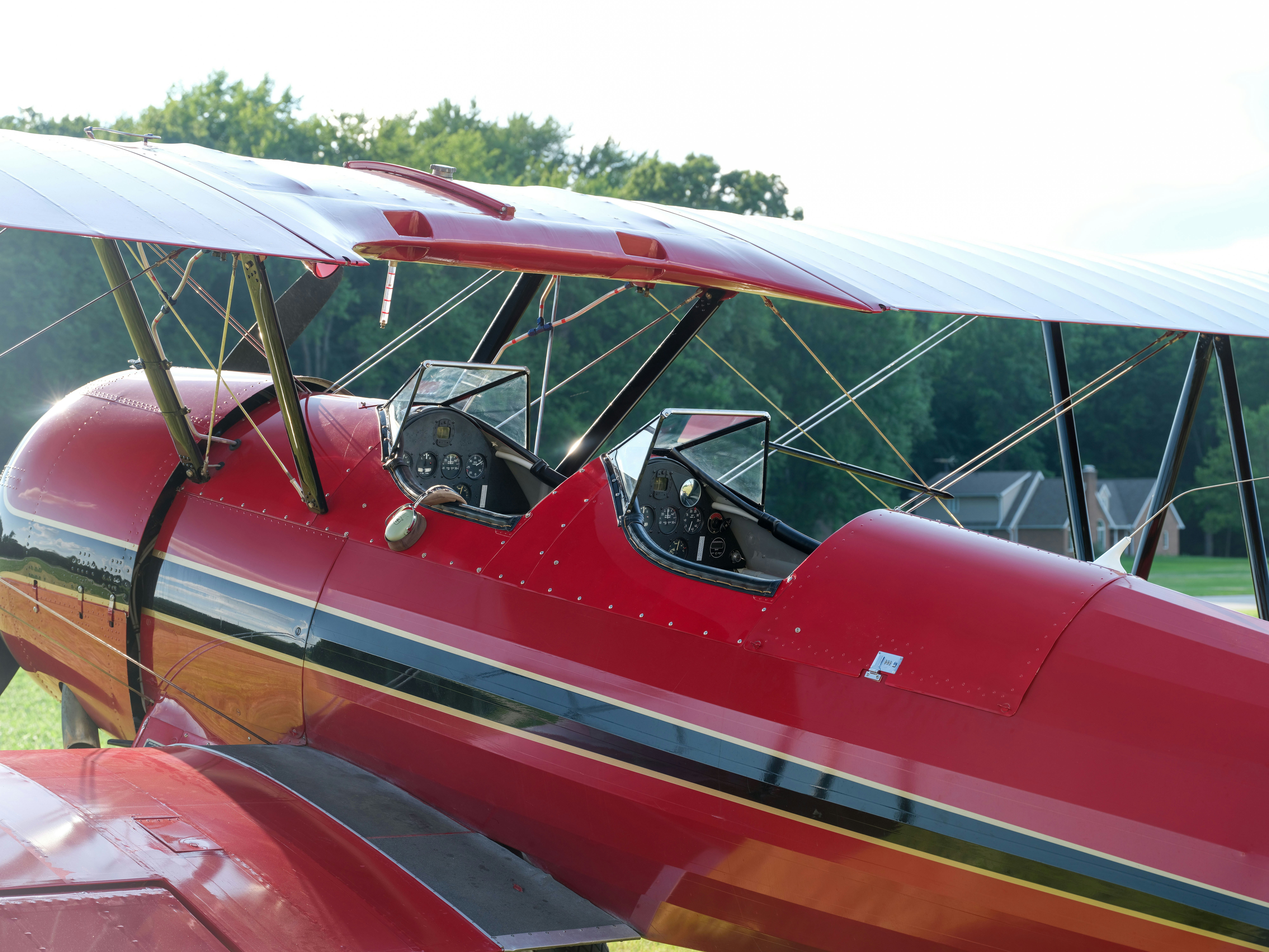 A red airplane parked on top of a lush green field