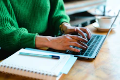 A person using a laptop on a wooden table