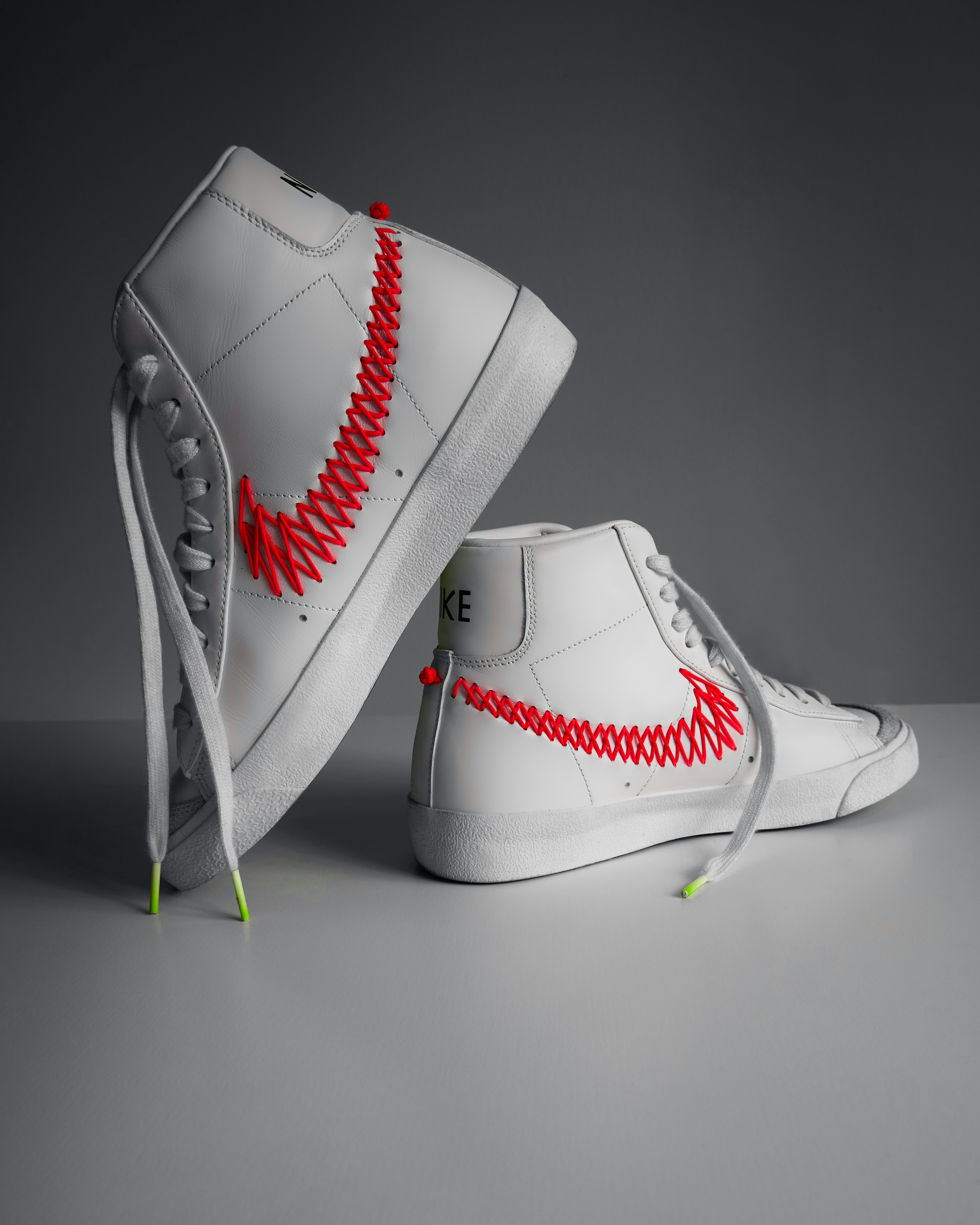 A pair of white shoes with red stitching on them