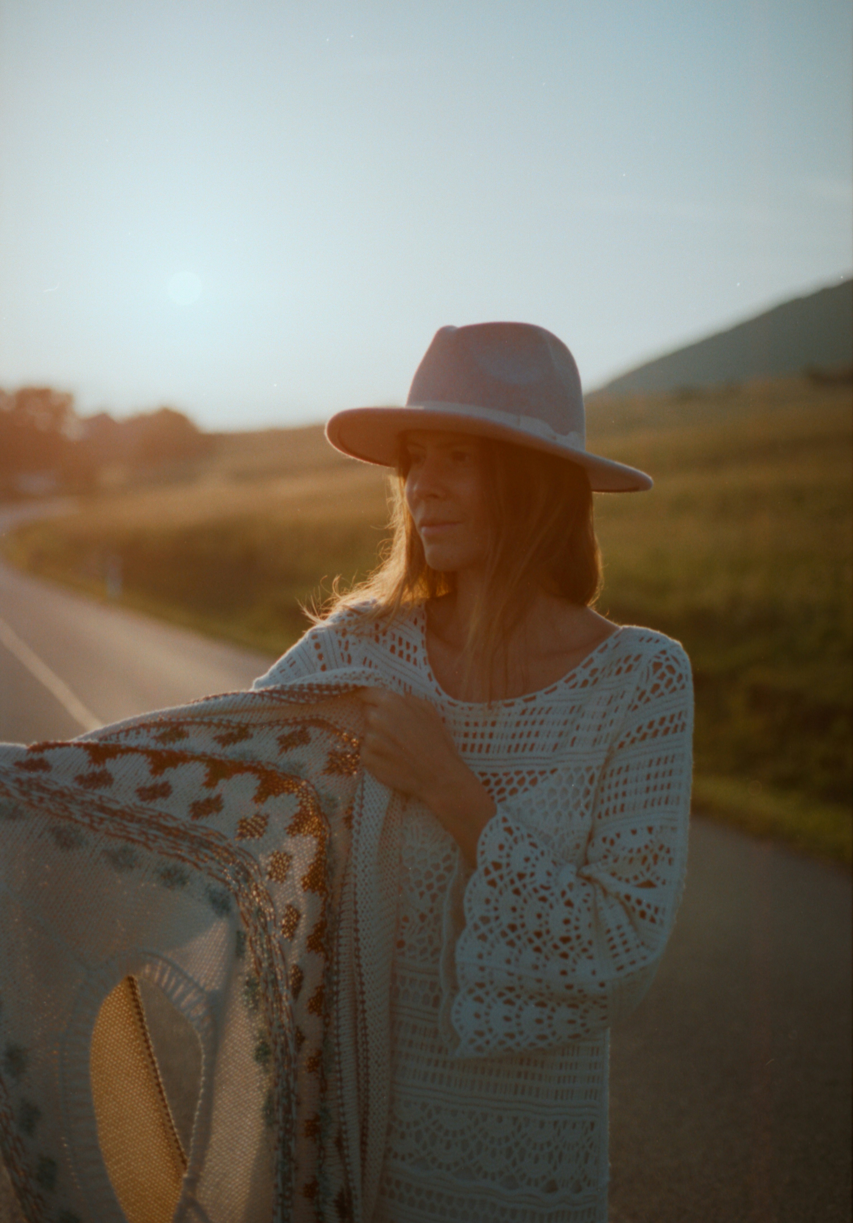 A woman with a hat and a scarf on a road