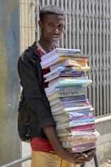 A man holding a large stack of books