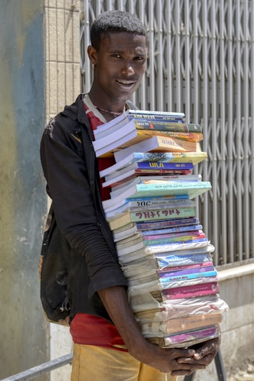 A man holding a large stack of books