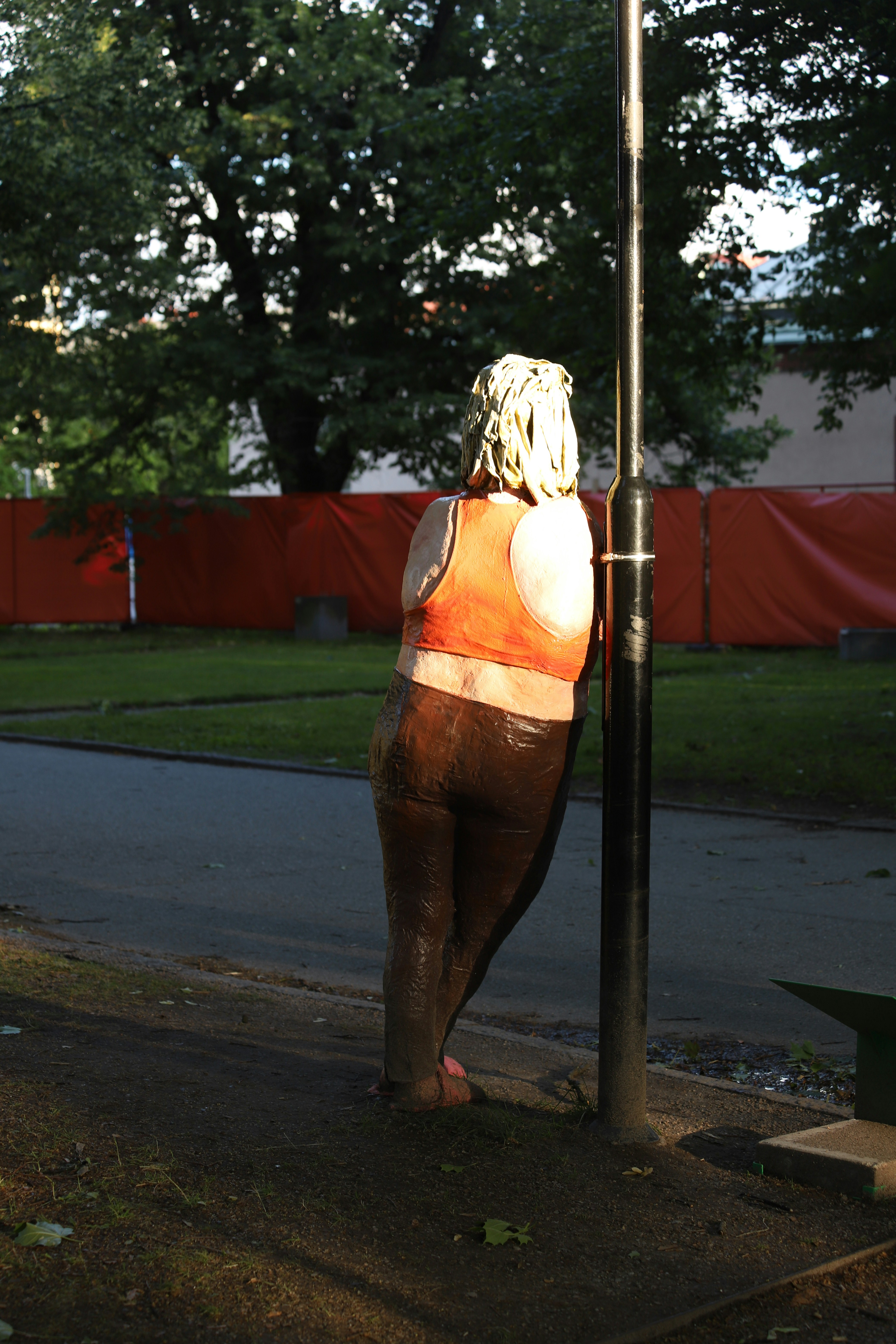 A statue of a woman leaning against a pole