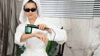 A woman in a bathrobe holding a hair dryer