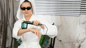 A woman in a bathrobe holding a hair dryer