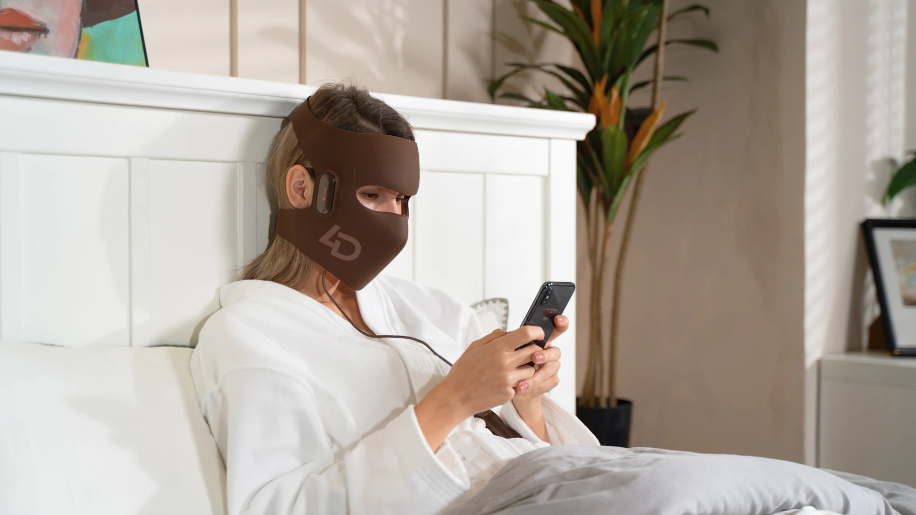 Woman using an LED light therapy beauty device during a skincare routine
