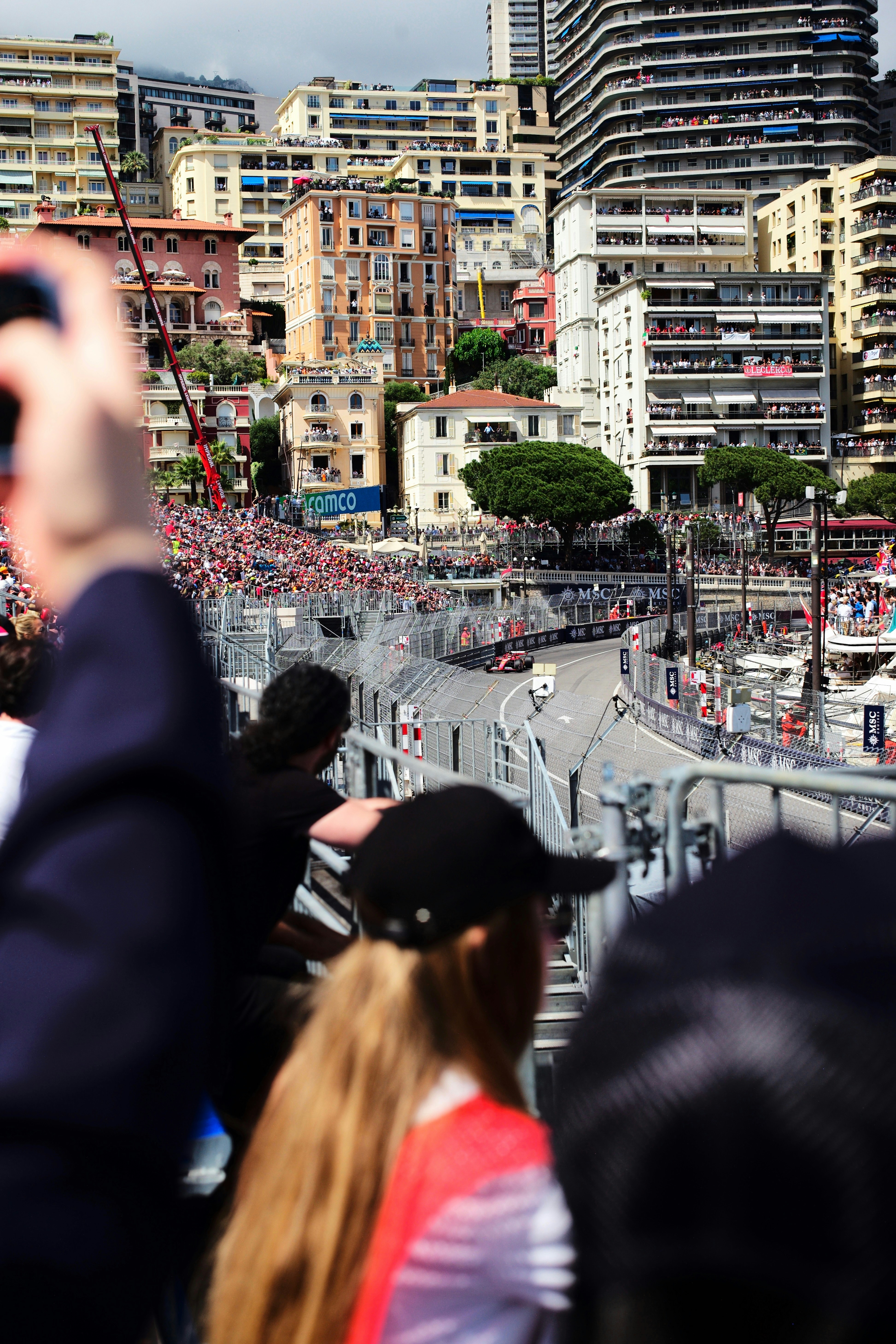 Formula 1 car racing through Monaco streets with harbor in background