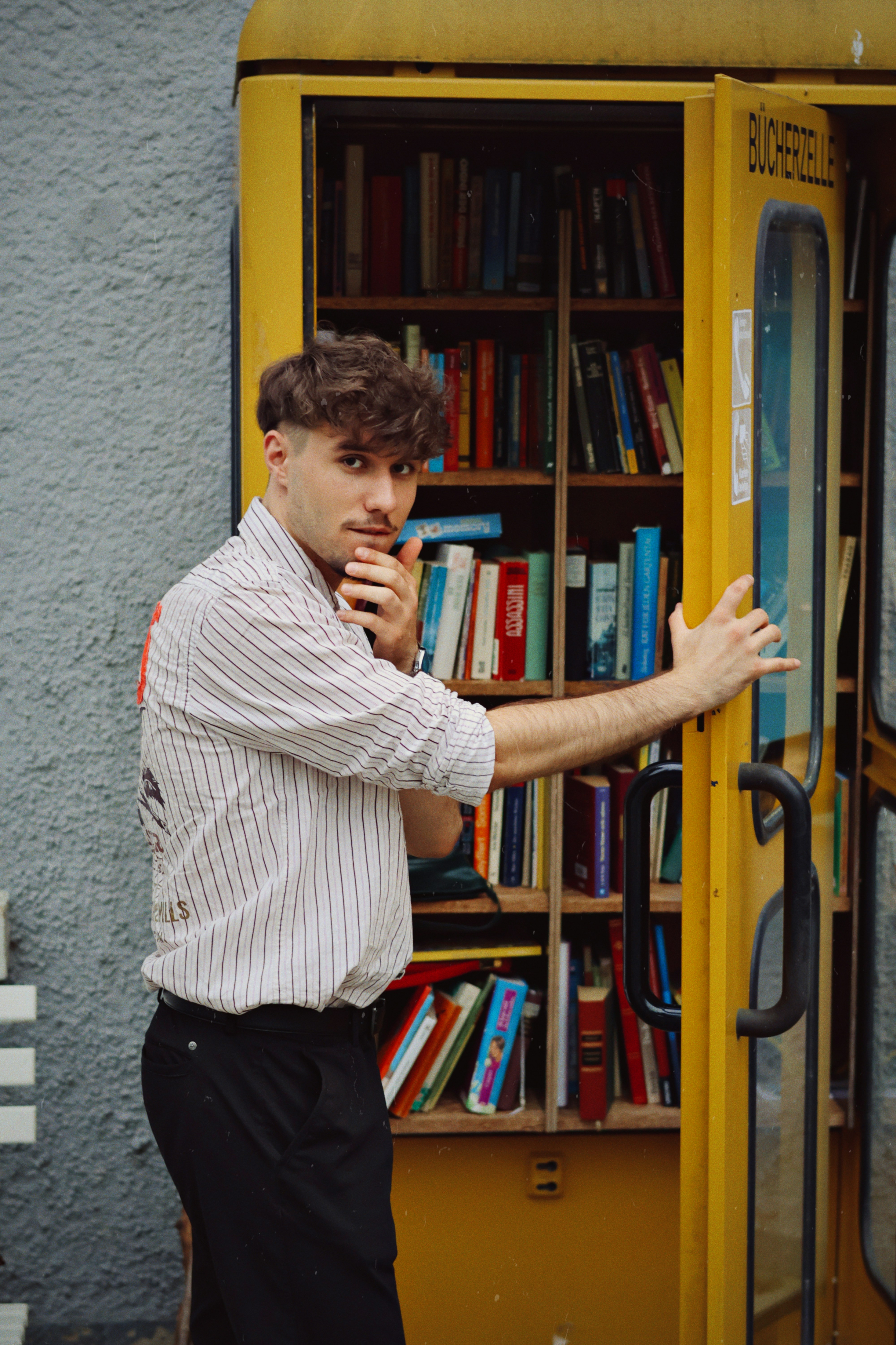 A man standing in front of a yellow book case