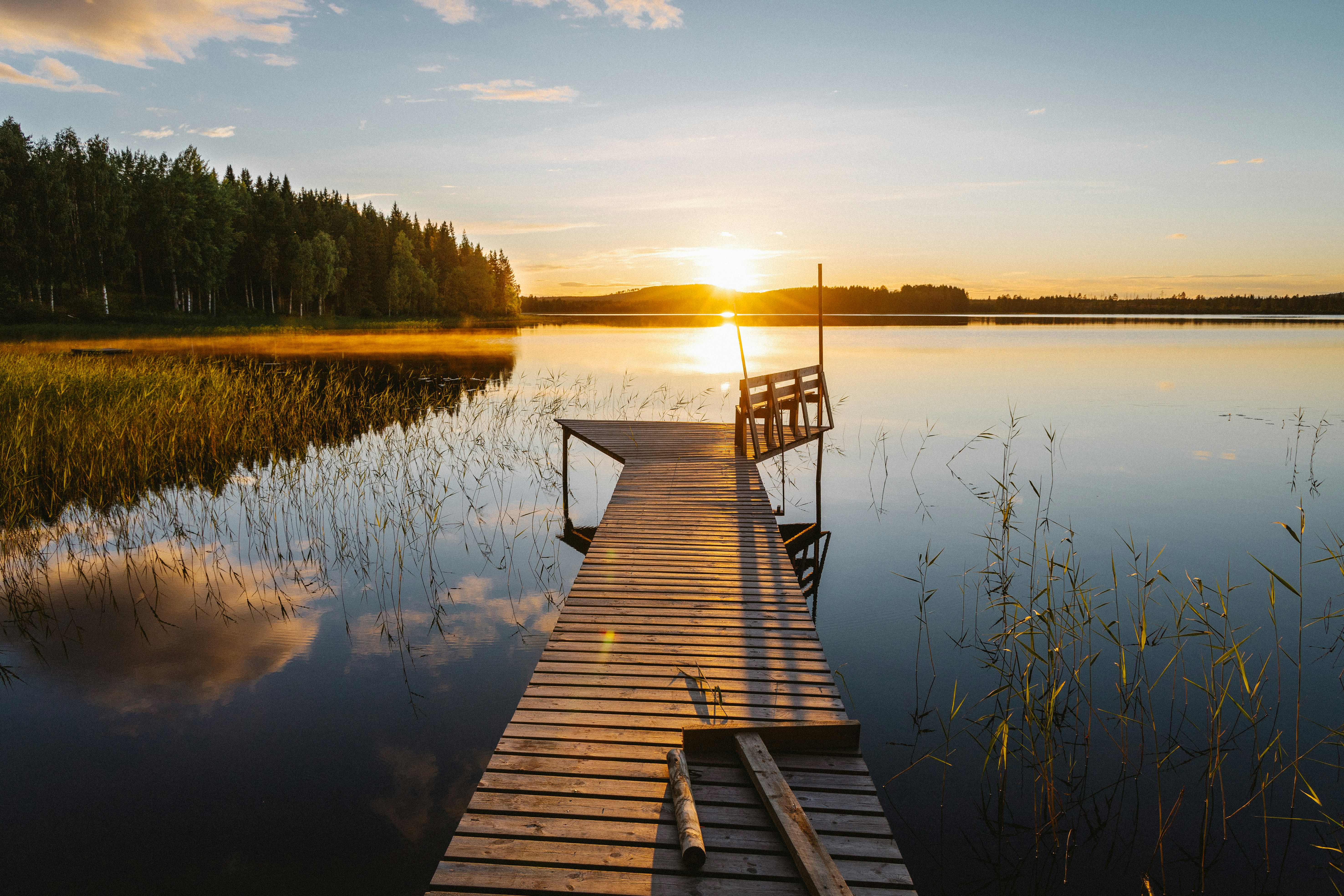 A dock on a lake with a sunset in the background