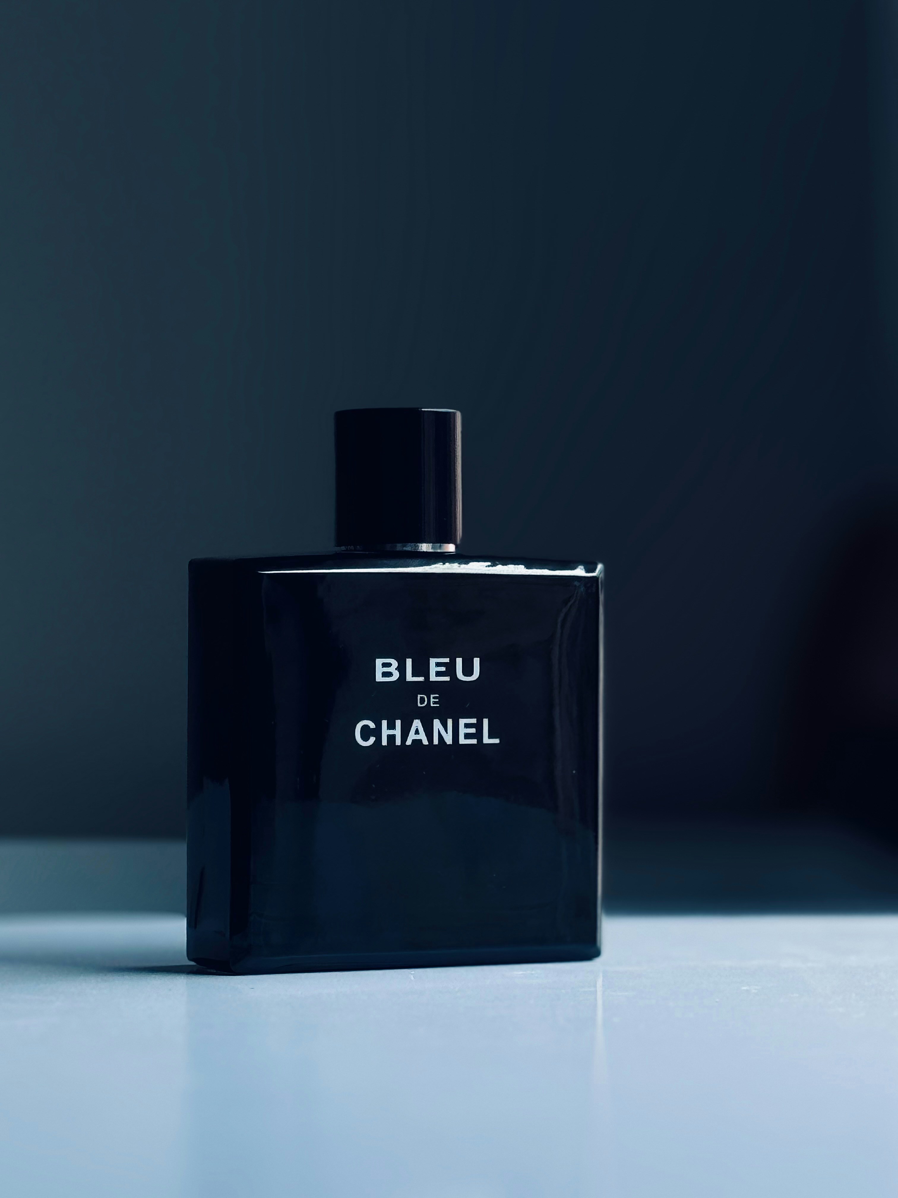 Chanel Bleu de Chanel navy blue rectangular bottle on a dark stone surface with cool blue ambient light