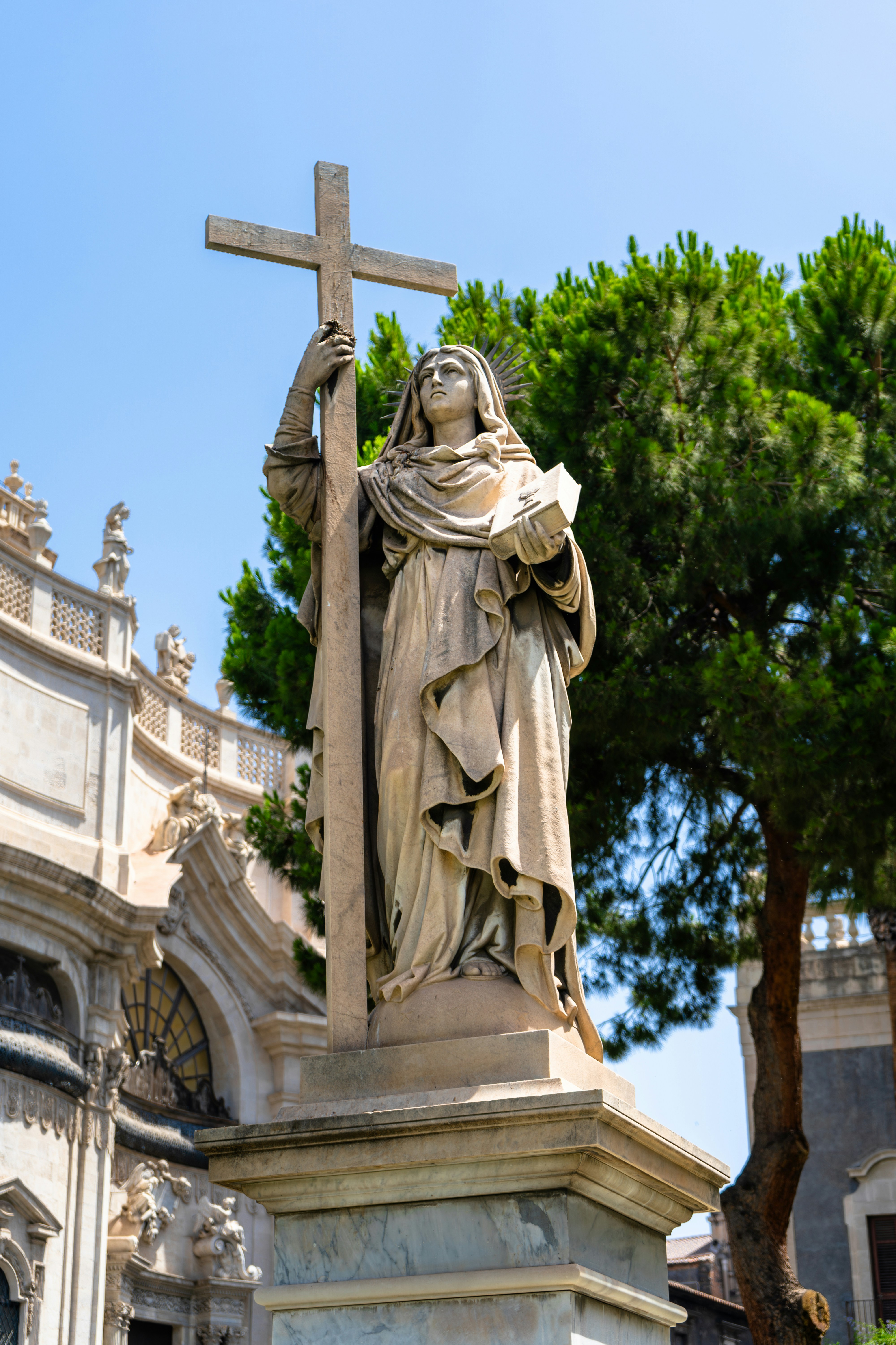 A statue of a person holding a cross in front of a building