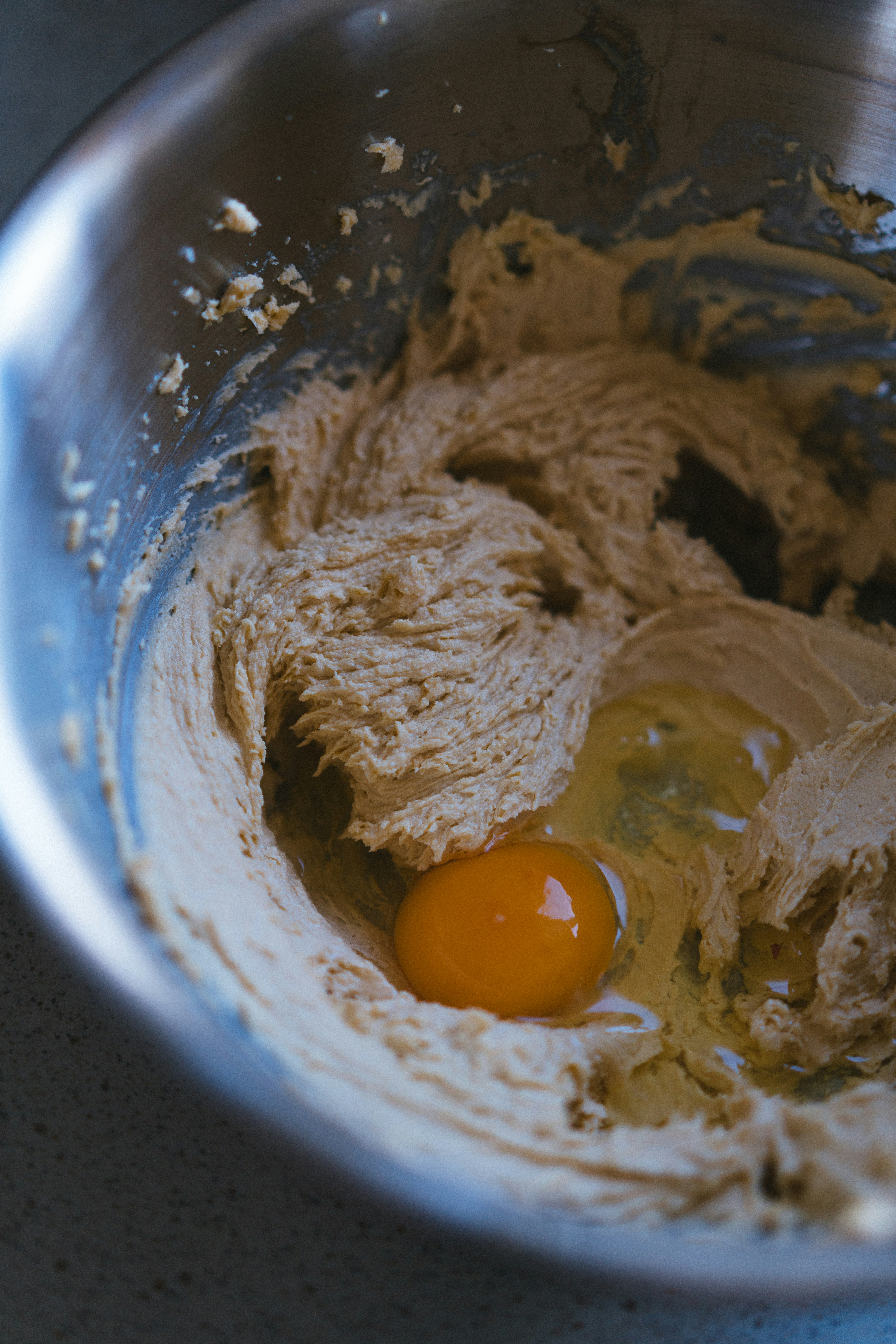 A metal bowl filled with batter and an egg