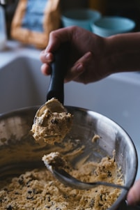 A person mixing something in a metal bowl