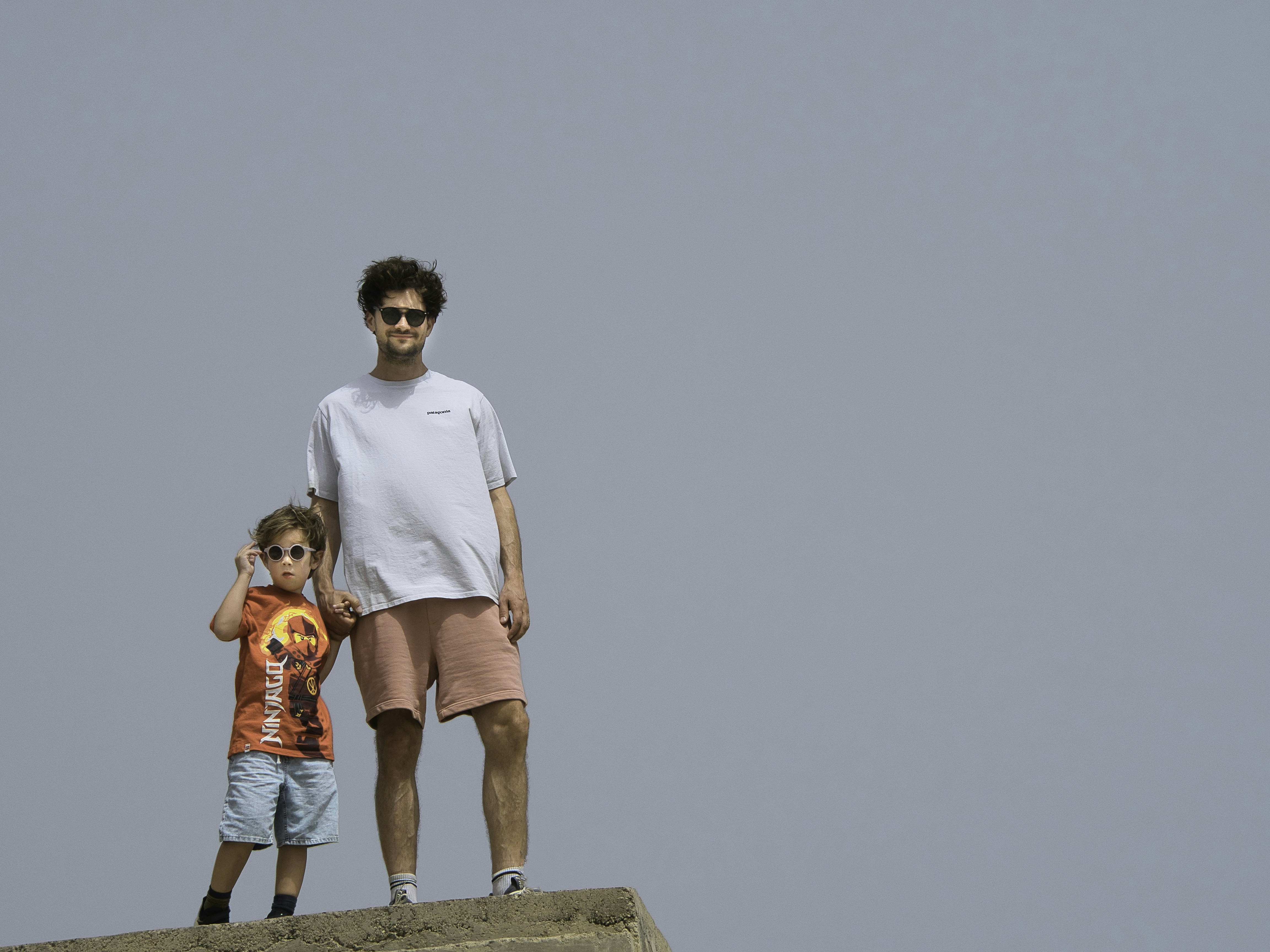 A man and a little girl standing on top of a rock