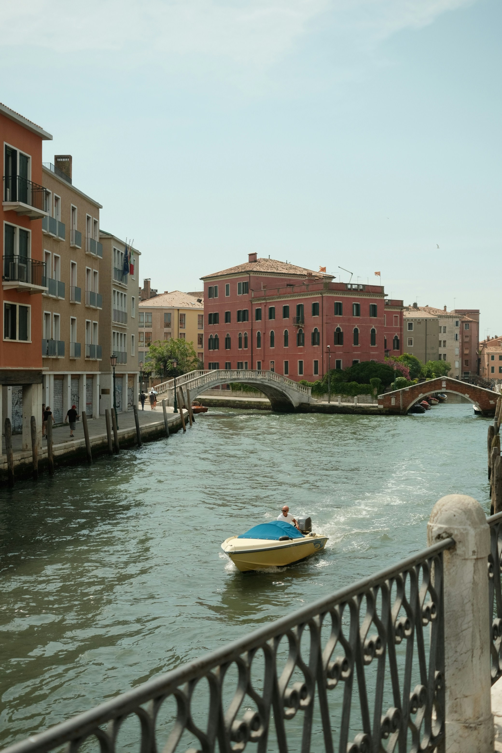 A boat traveling down a river next to tall buildings