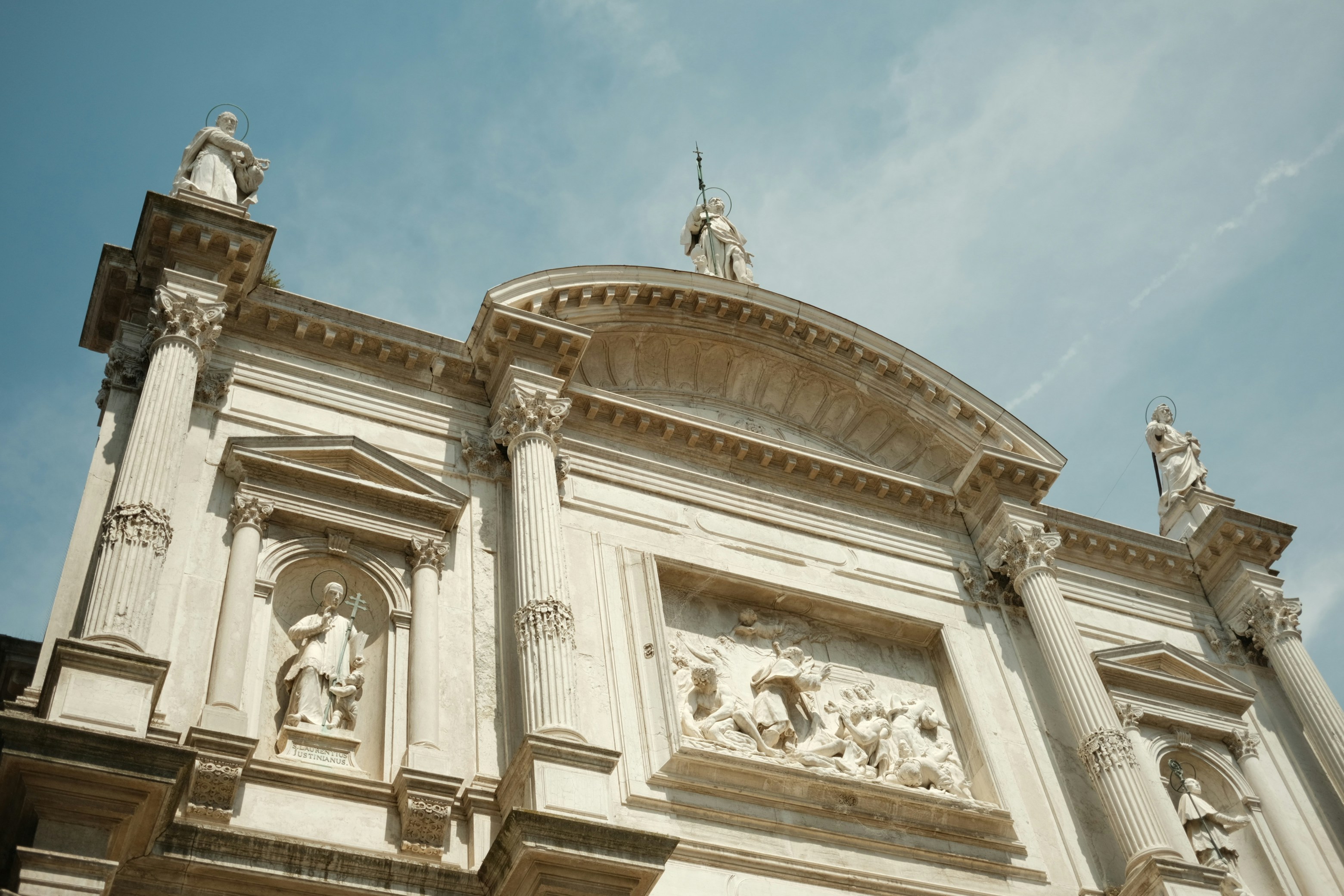 A white building with statues on the side of it
