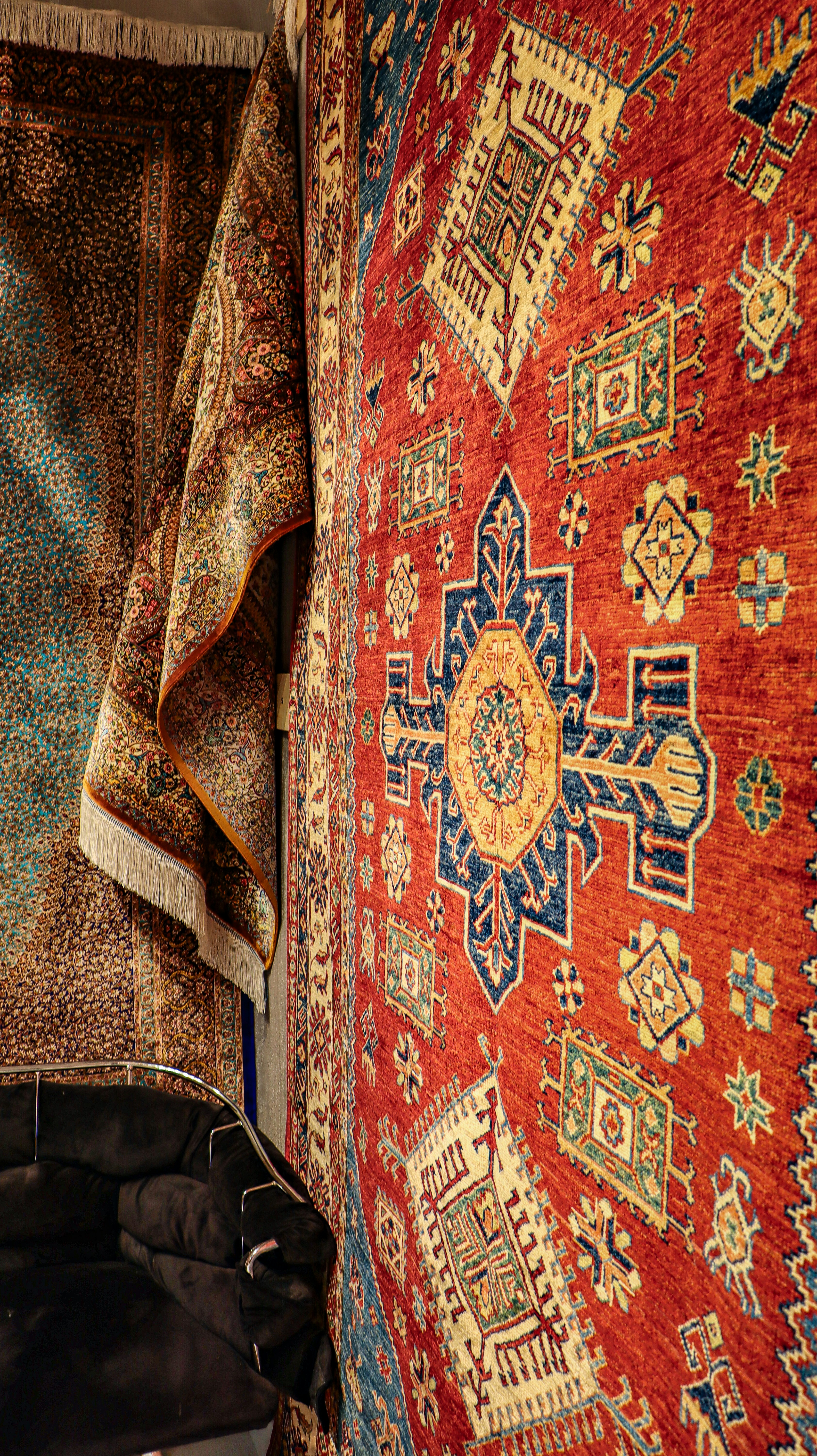 A rug is hanging on a wall next to a purse