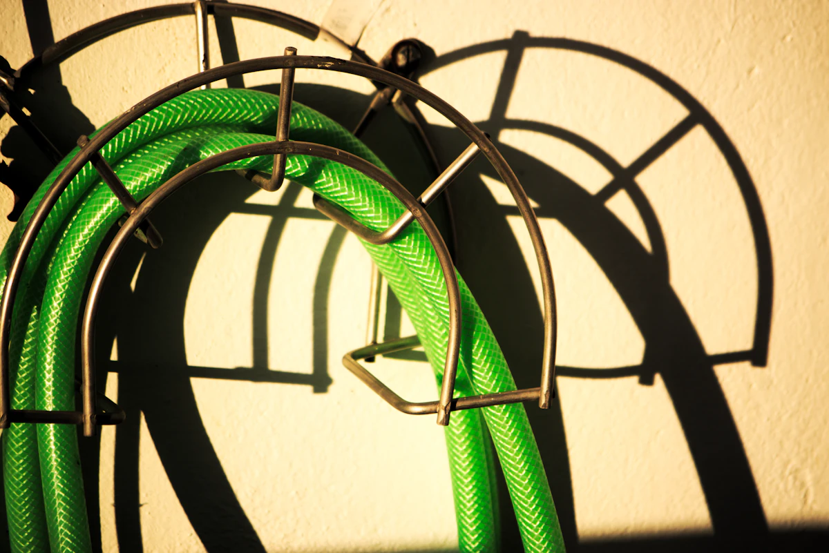 A couple of green hoses hanging from a wall