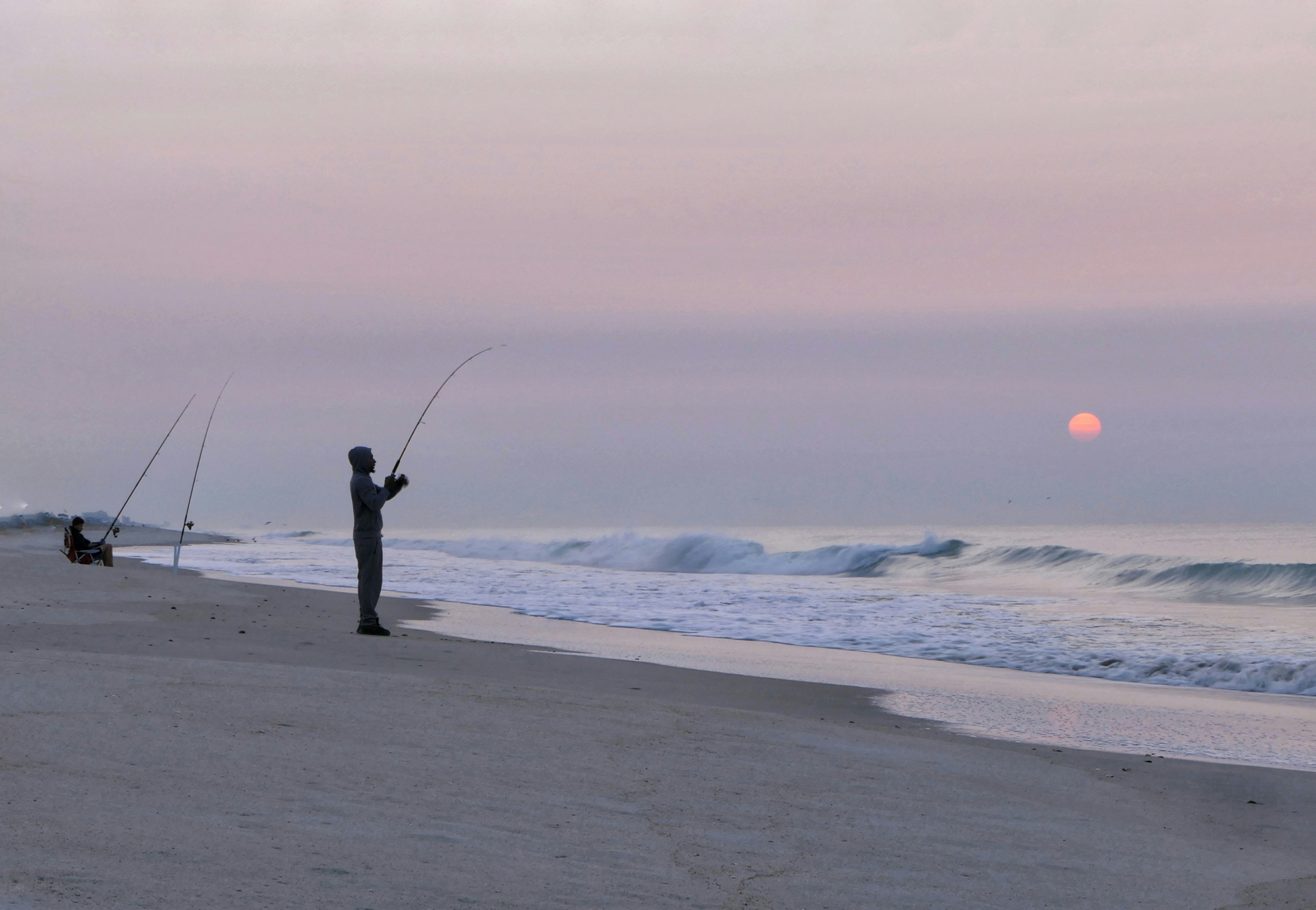 A man standing on top of a sandy beach next to the ocean