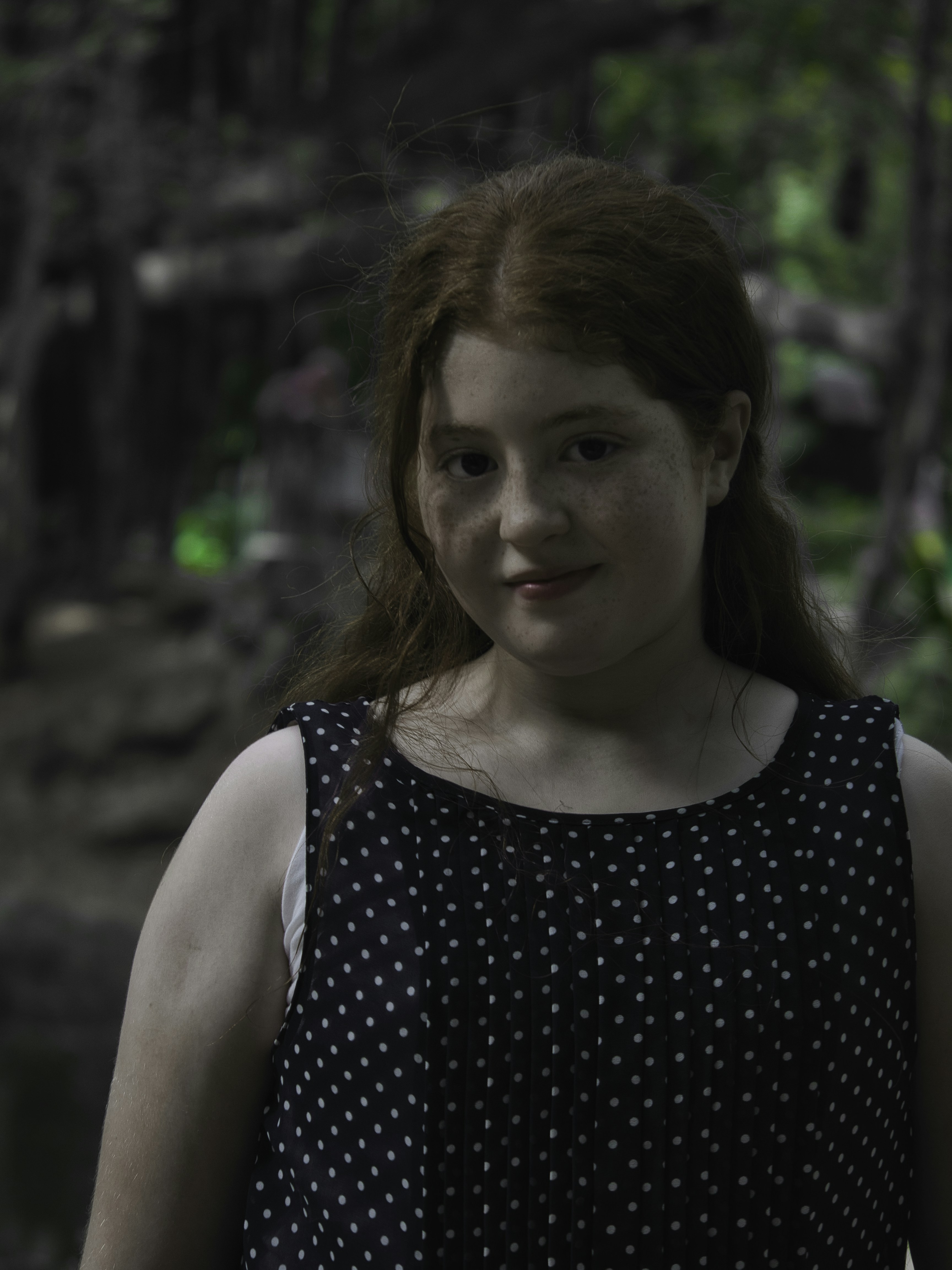 A girl in a black and white dress standing in front of a pond