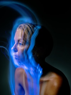 A woman with blue hair is smoking a cigarette
