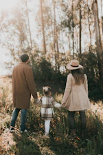 A man and a woman walking through a forest holding hands