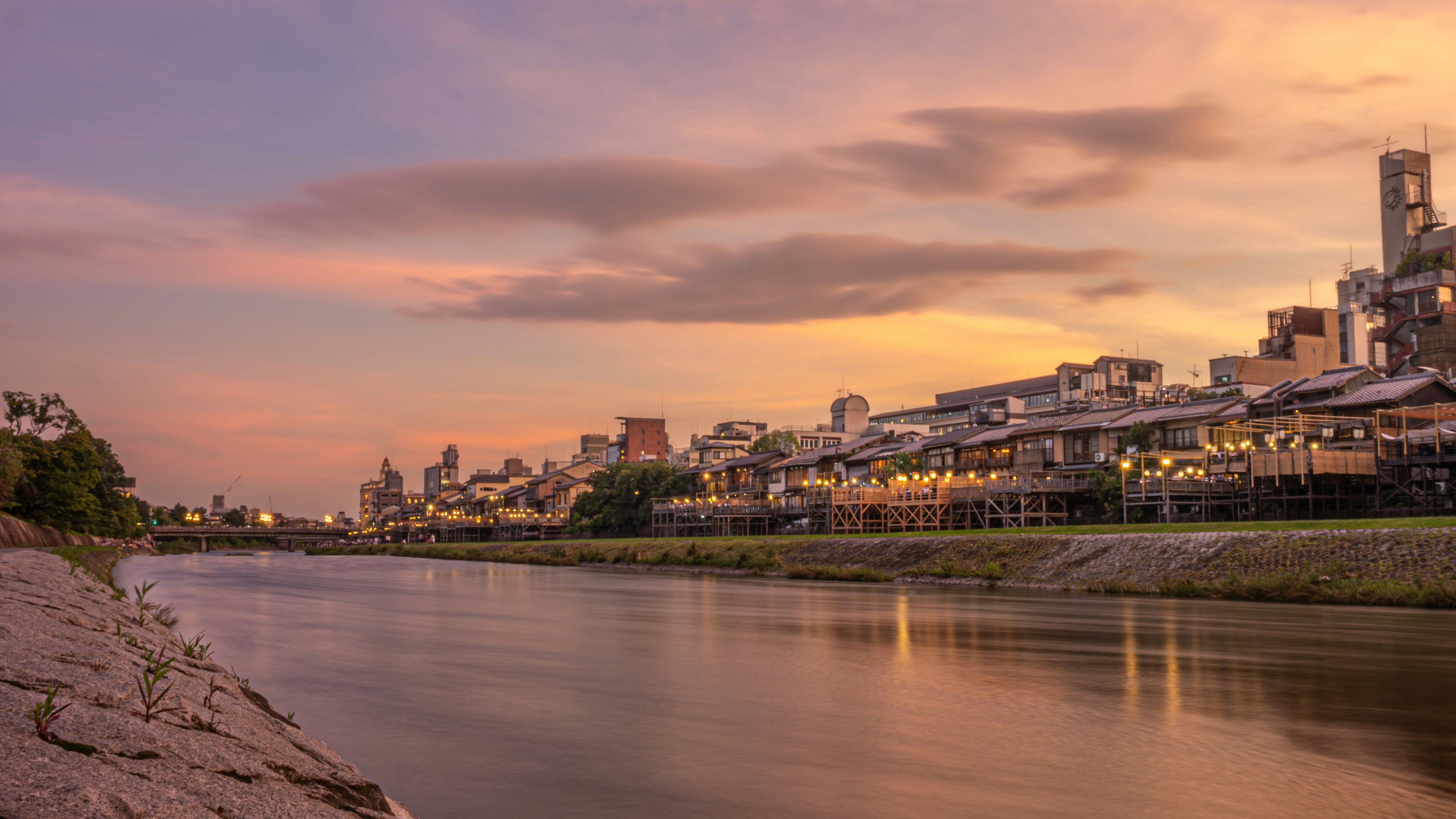 A view of a river with a city in the background, Kamo River at sunset, Kyoto, Japan.