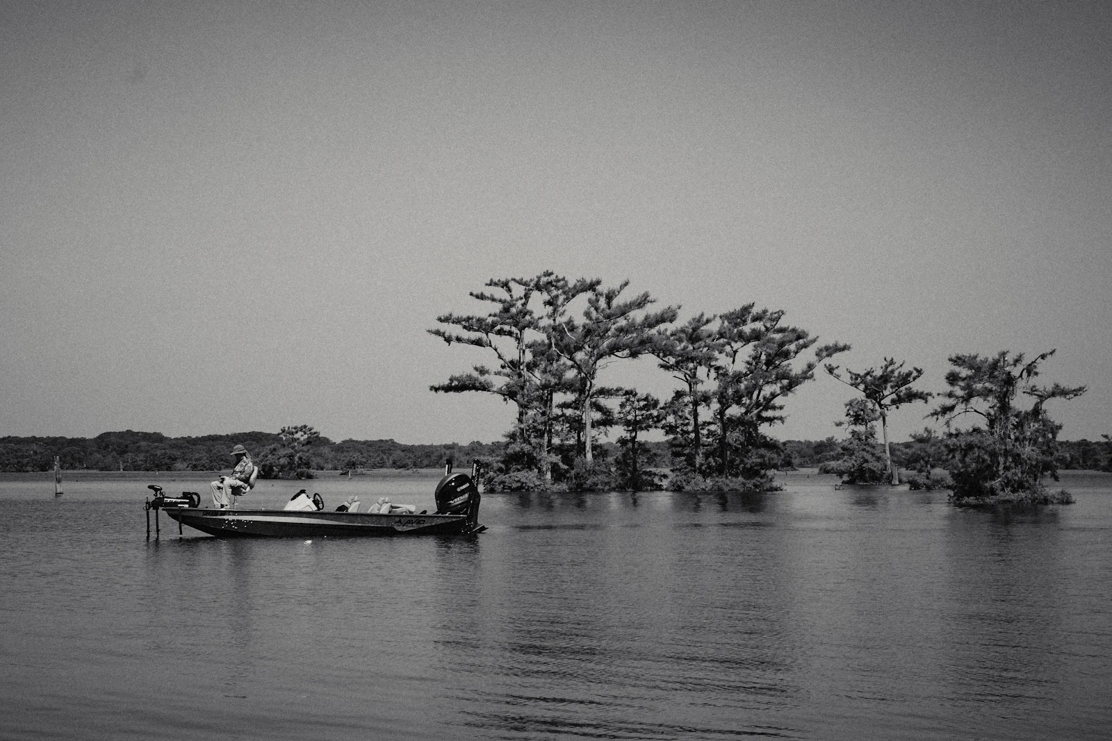 A small boat sitting still on wide brown water.