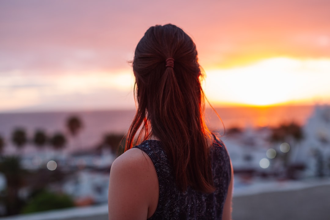 A woman standing on top of a roof looking at the sunset,