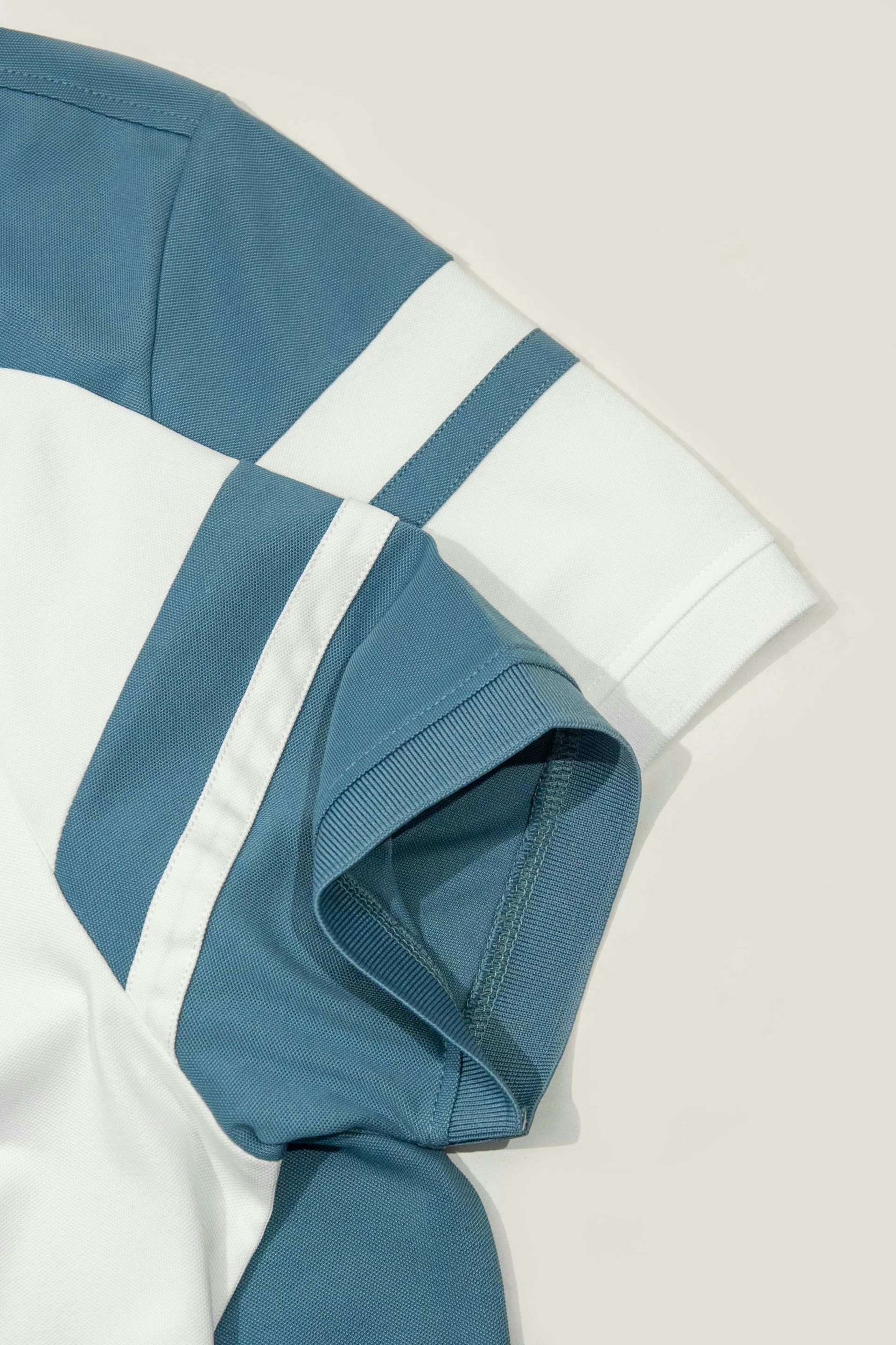 A blue and white shirt laying on top of a white table