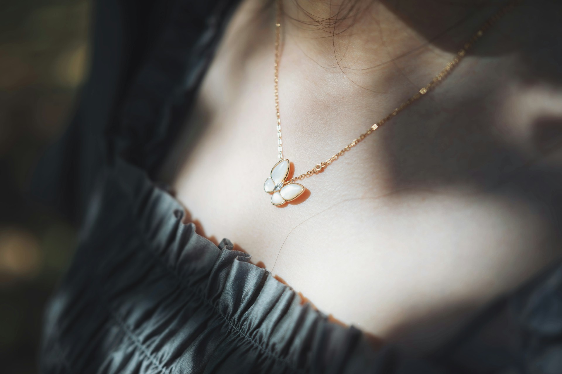 A woman wearing a necklace with a butterfly on it