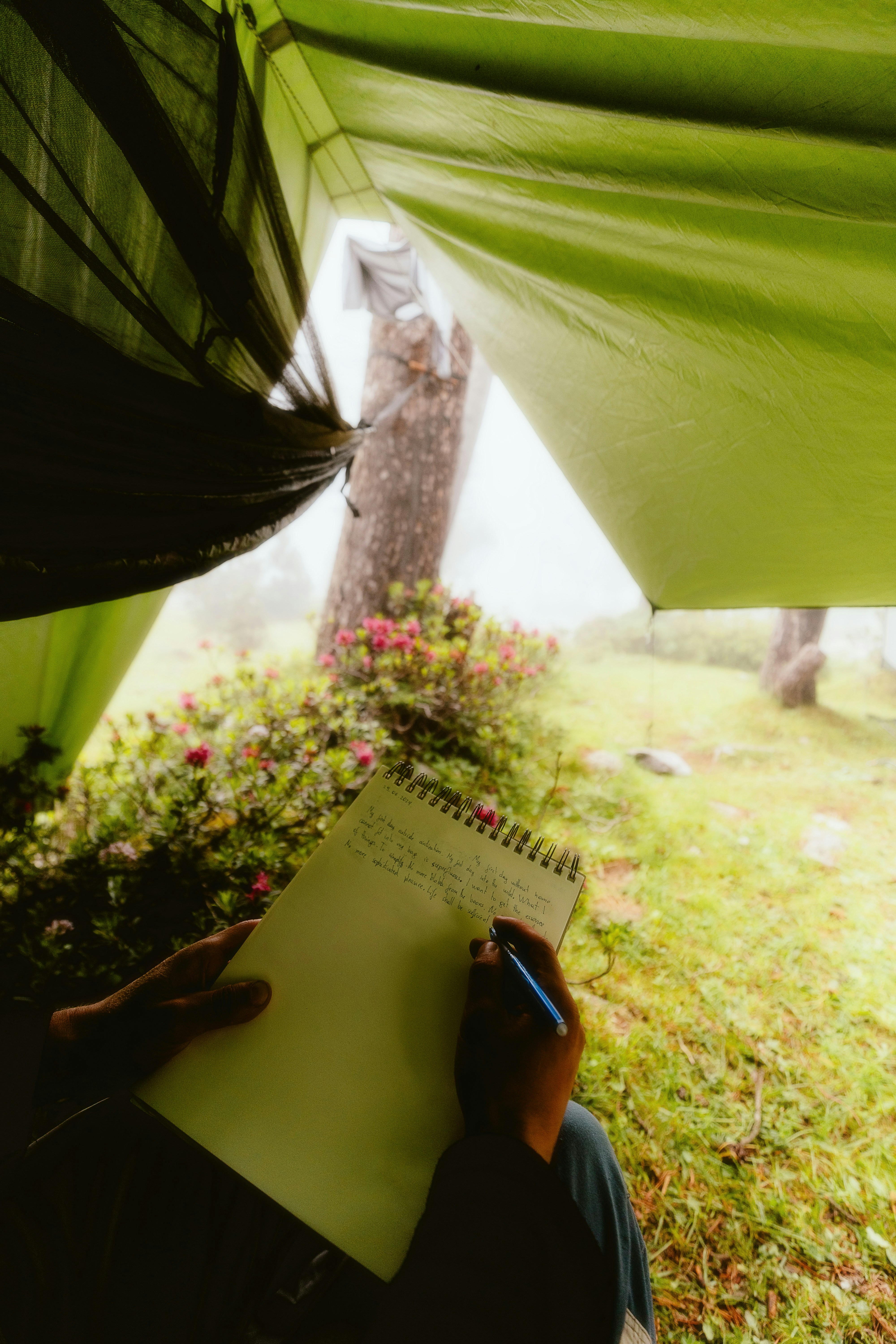 A person sitting in a tent writing on a notepad