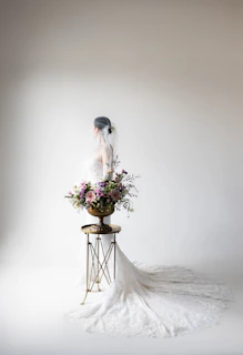 A woman in a wedding dress sitting on a stool