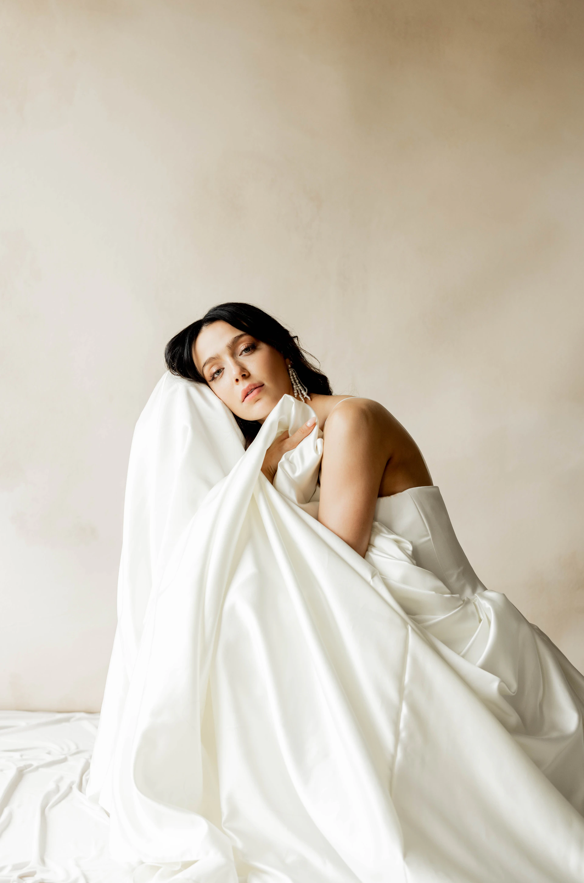 A woman in a white dress sitting on a bed