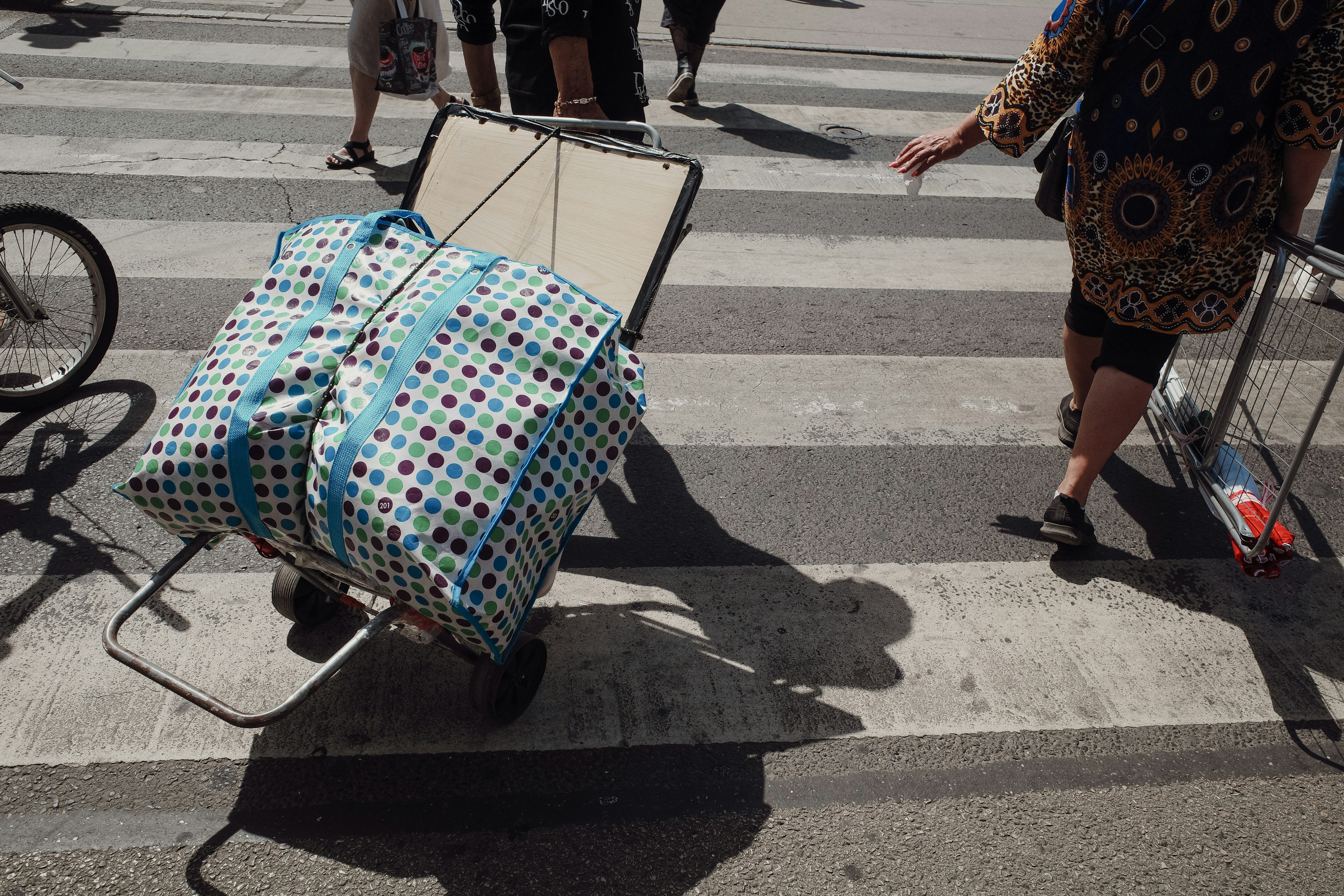 A woman pushing a cart with a suitcase on it, 