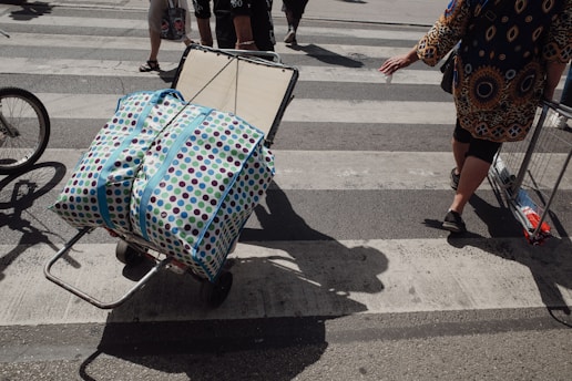 A woman pushing a cart with a suitcase on it