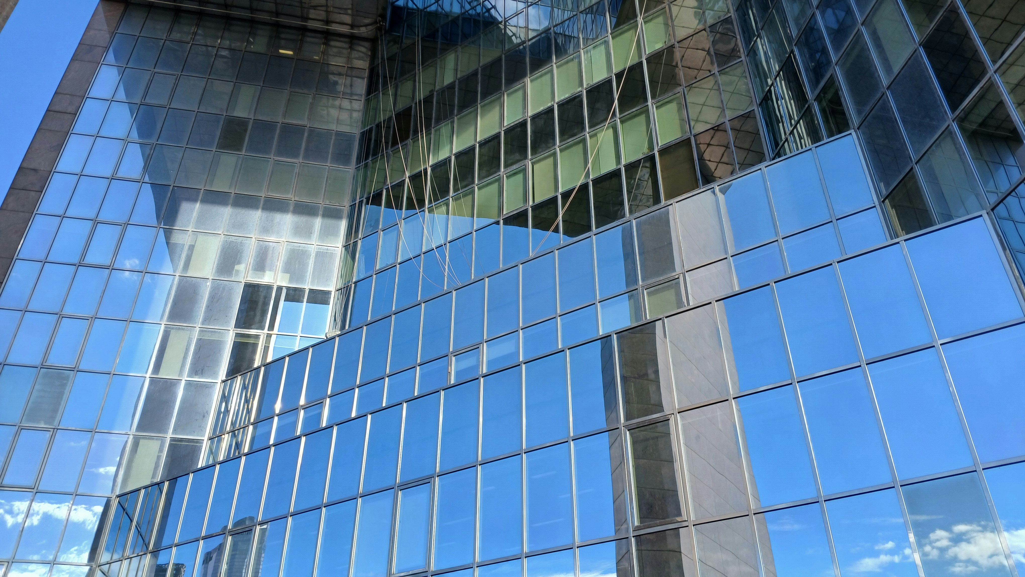 Modern corporate headquarters glass building exterior on clear day with blue sky