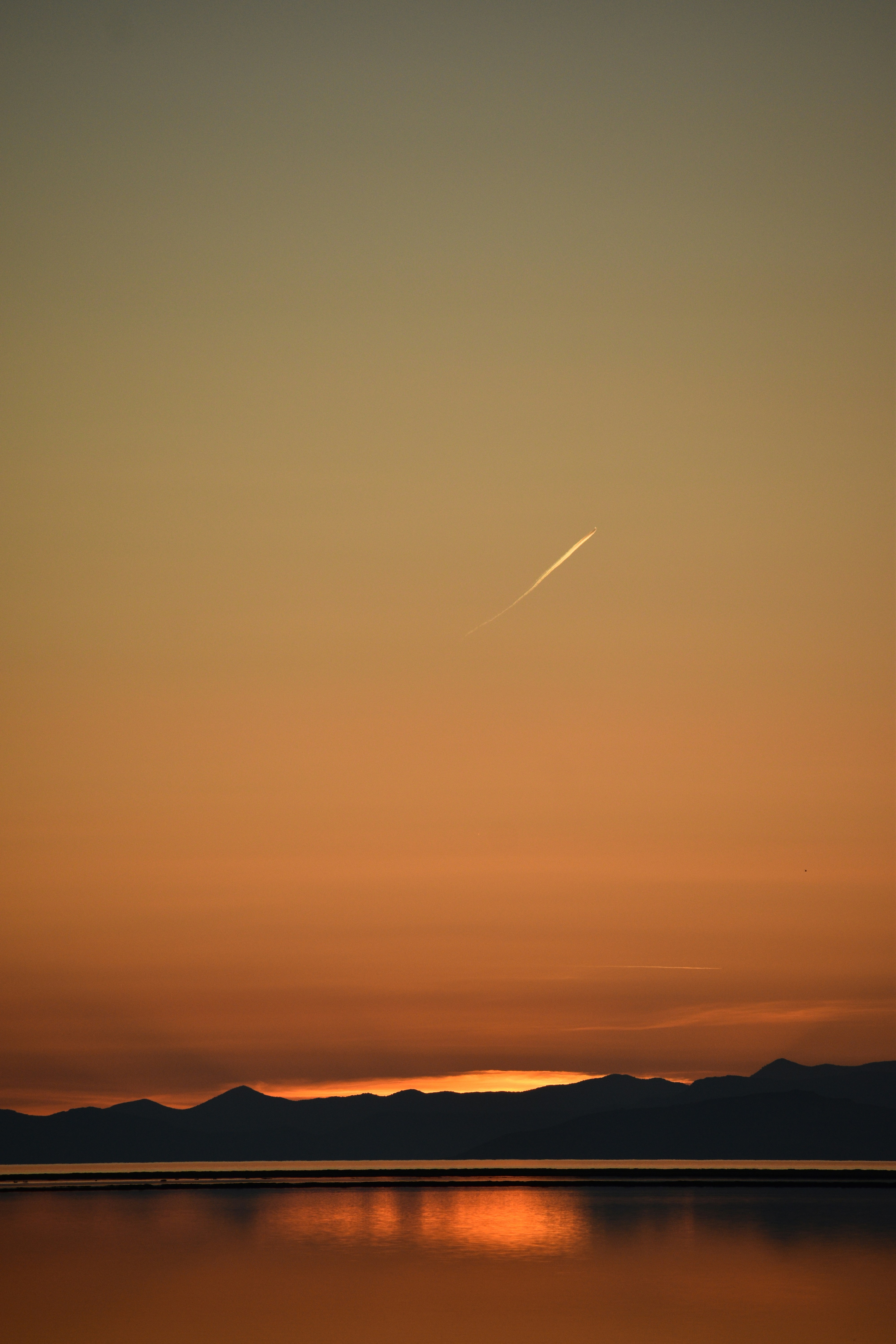 A plane flying over a body of water at sunset photo – Free Sunset Image ...