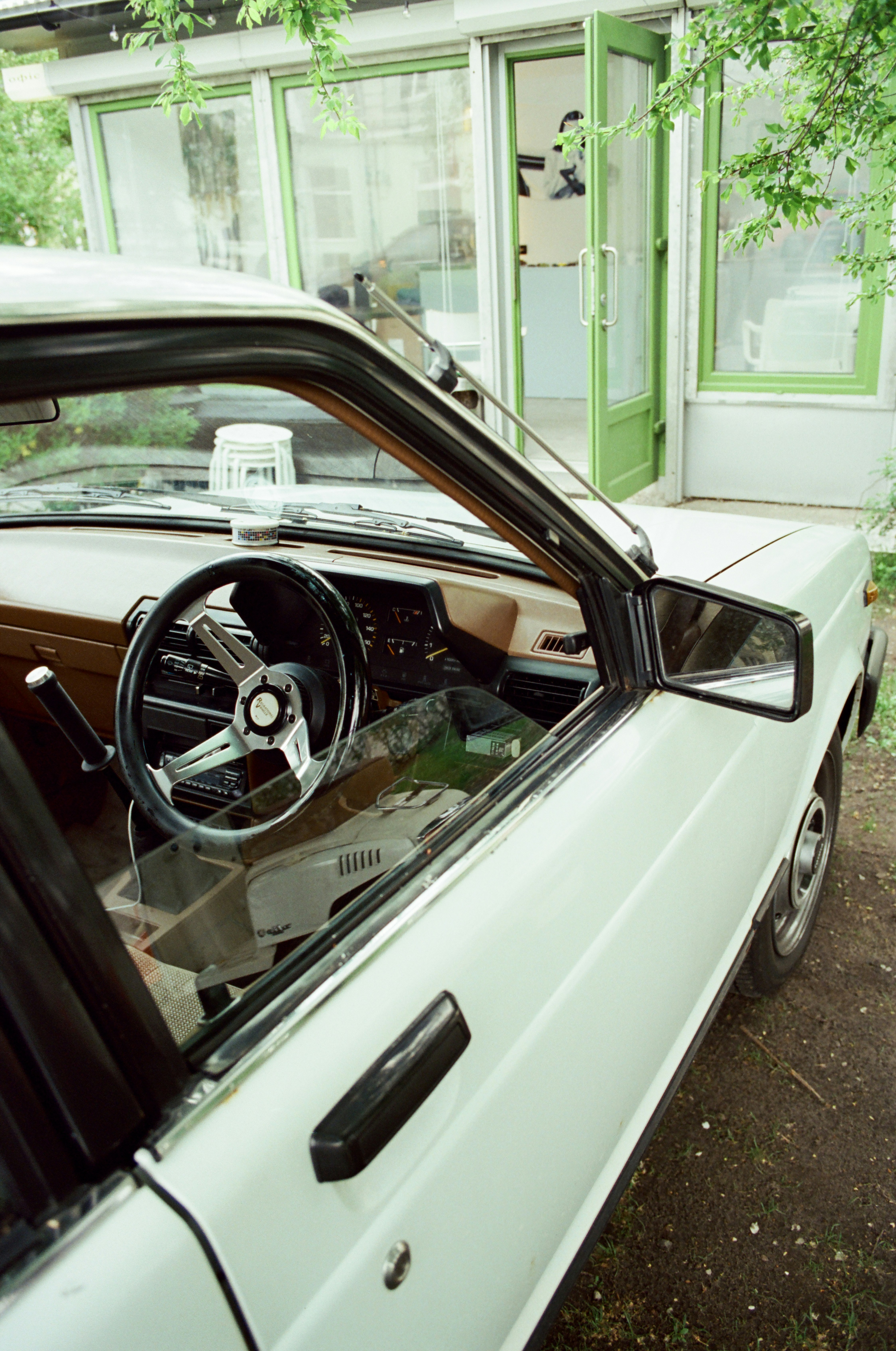 A white car parked in front of a green building