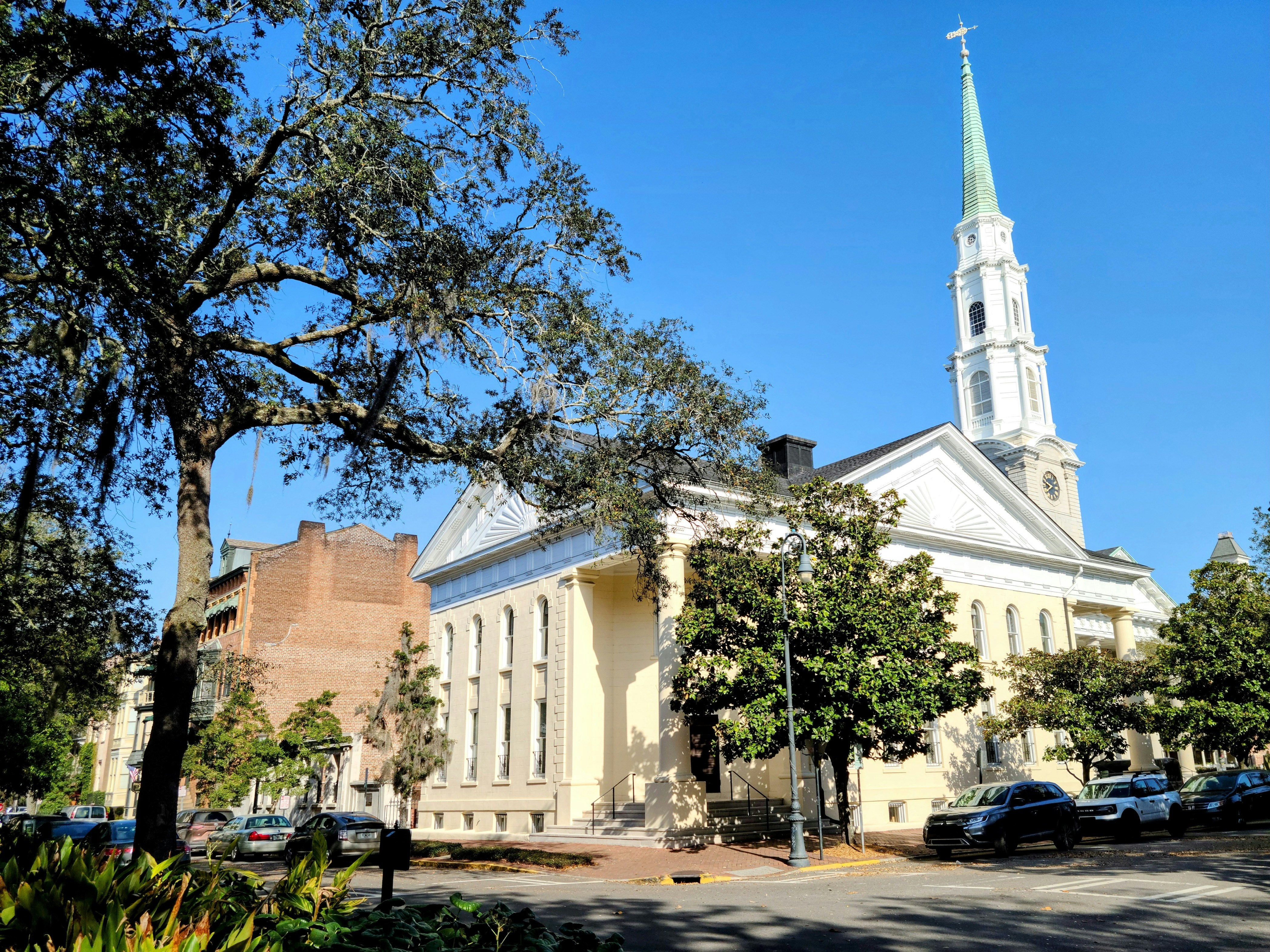 Una iglesia con un campanario y árboles frente a ella