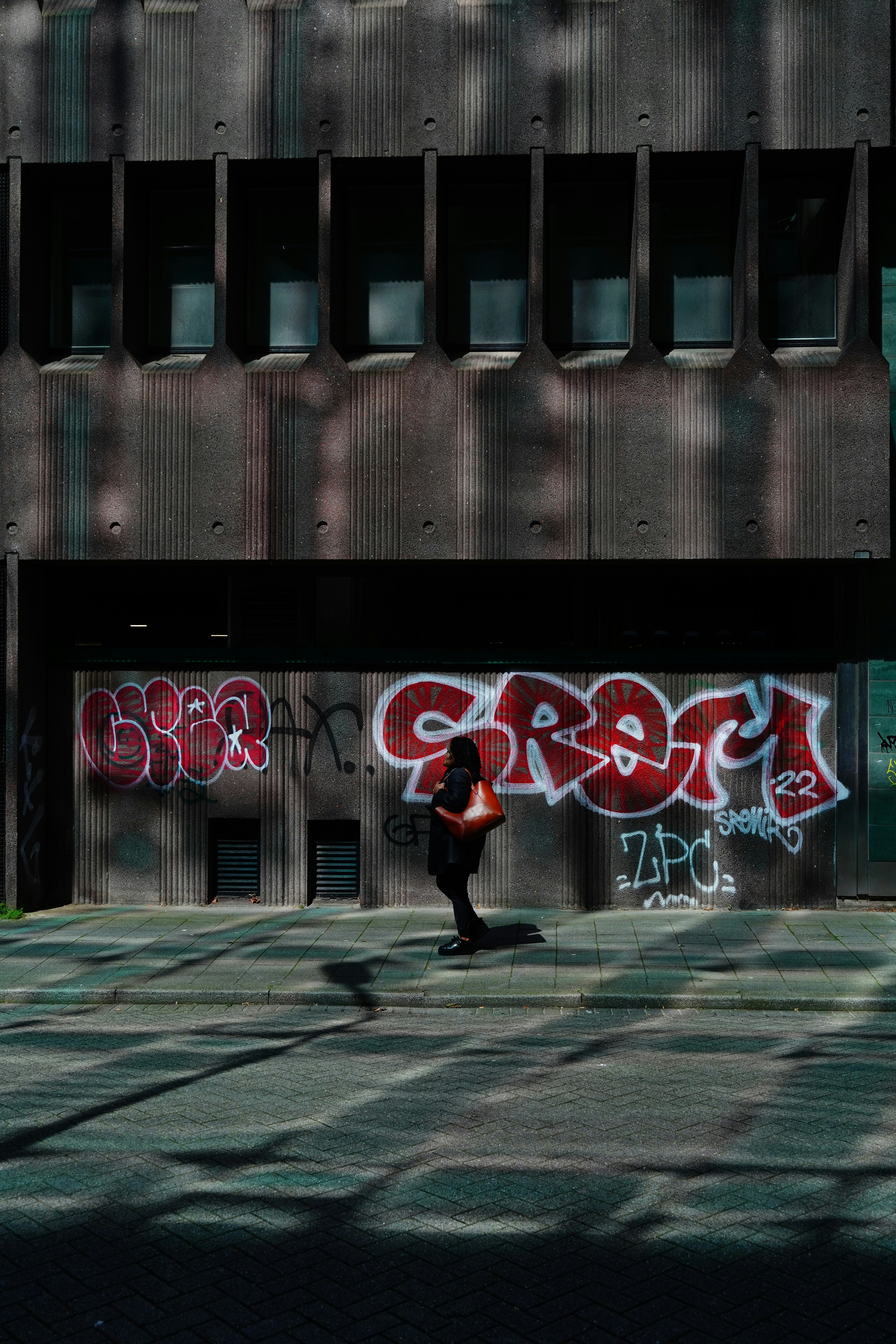 A person walking in front of a building with graffiti on it