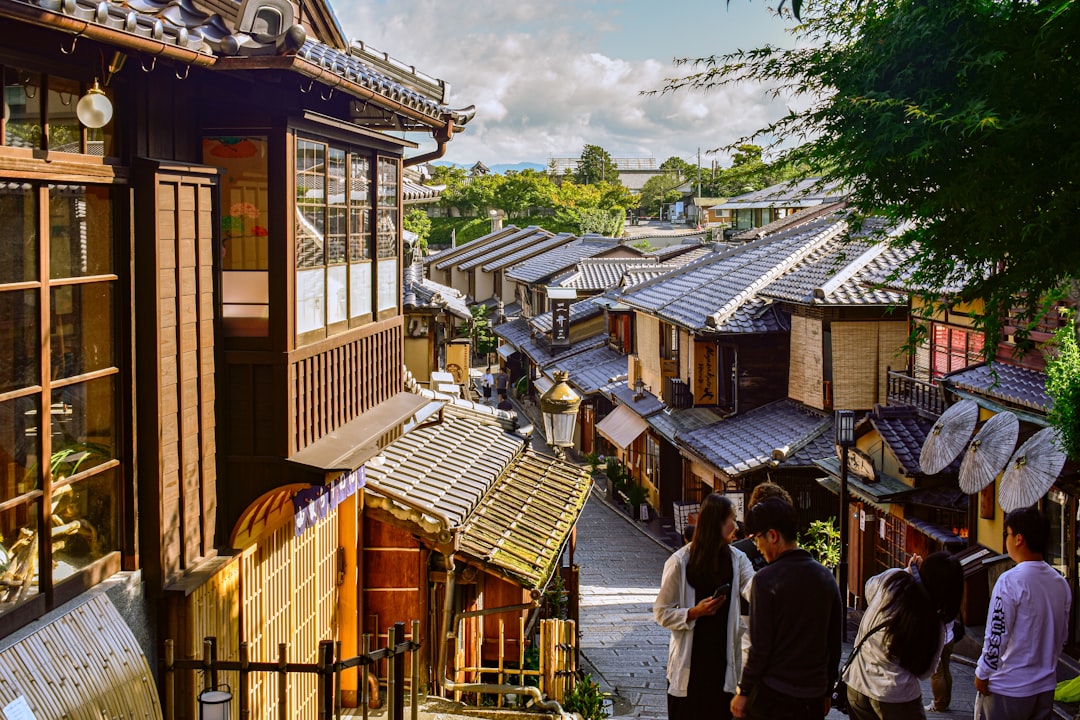 A group of people standing outside of a building, traditional kyoto street