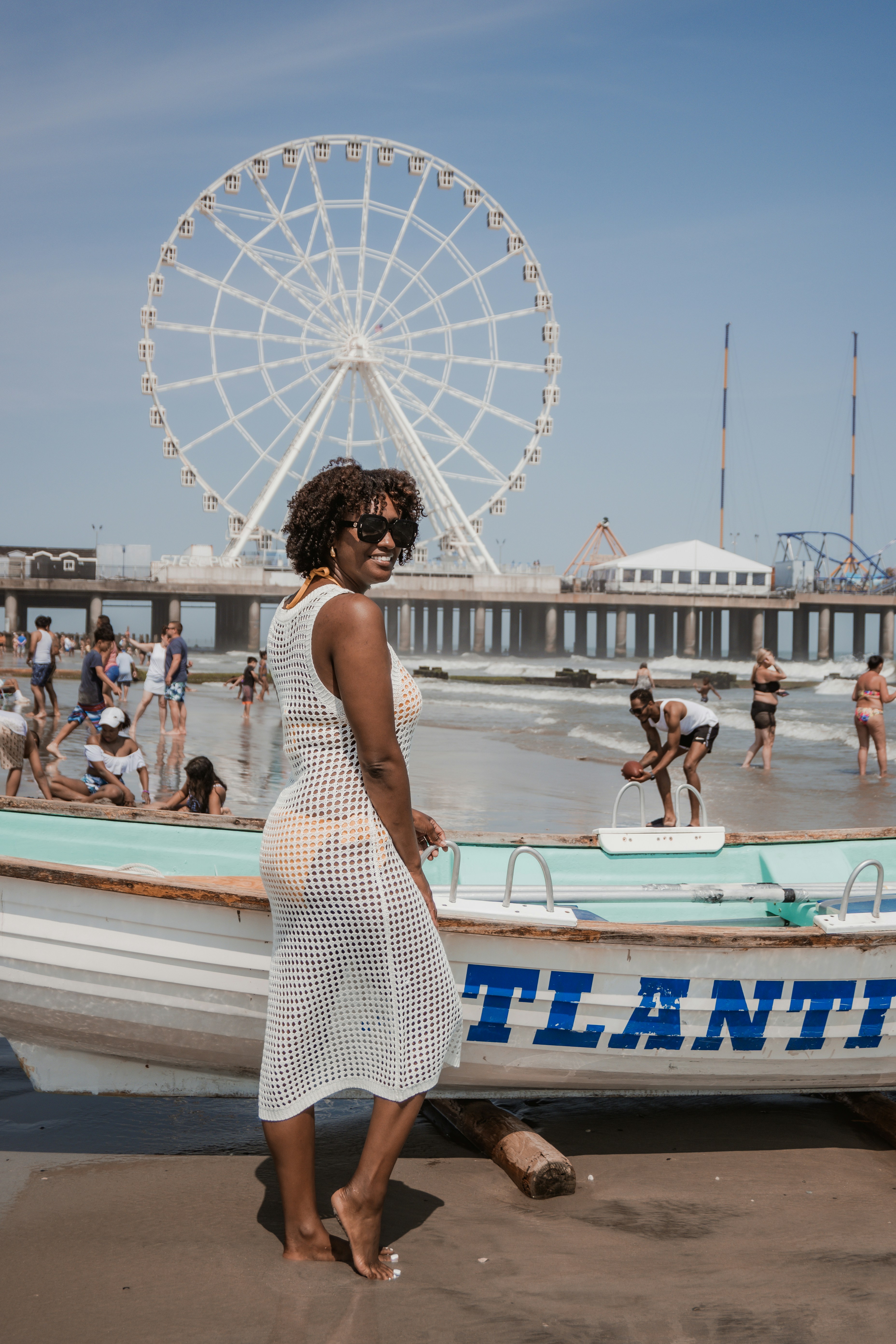 A woman in a white dress standing next to a boat