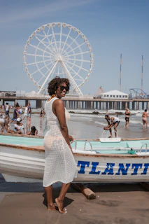 A woman in a white dress standing next to a boat