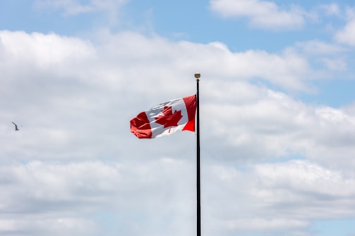 A canadian flag flying in the wind on a cloudy day